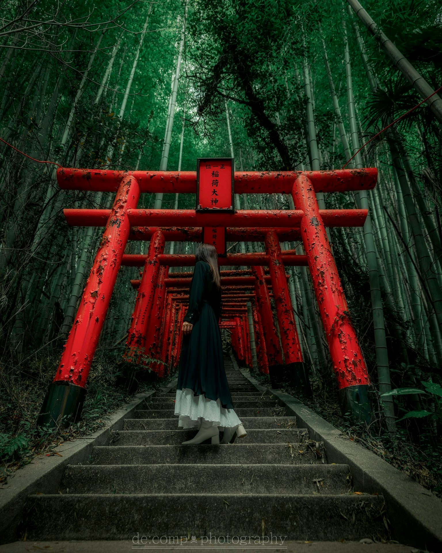 A person ascending stairs among red torii gates in a green bamboo forest