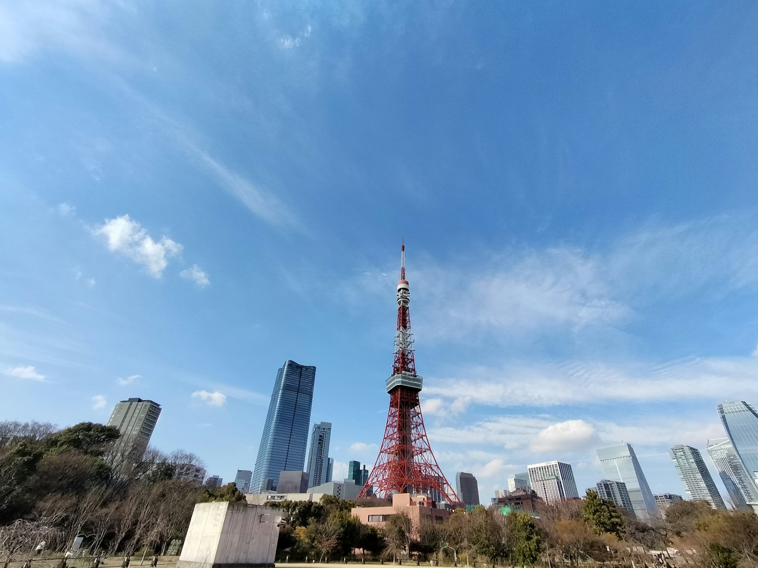 Tokyo Tower, die unter einem blauen Himmel in einer Stadtlandschaft steht