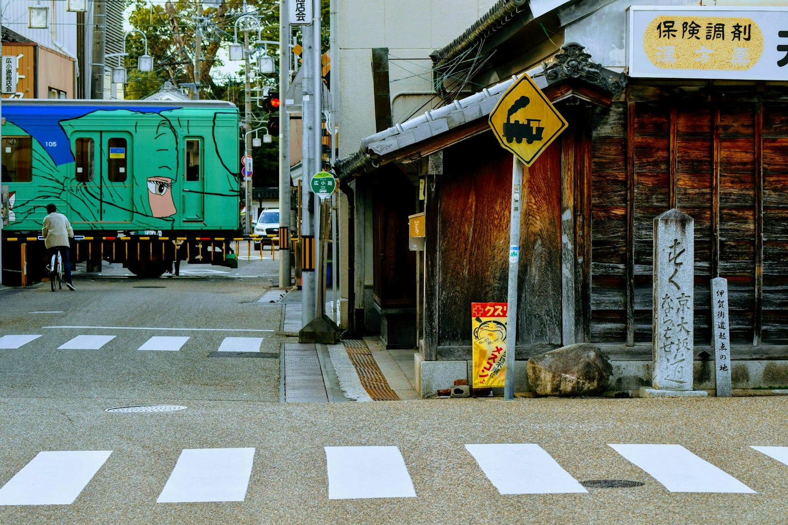 Intersection featuring a blue train and an old wooden building
