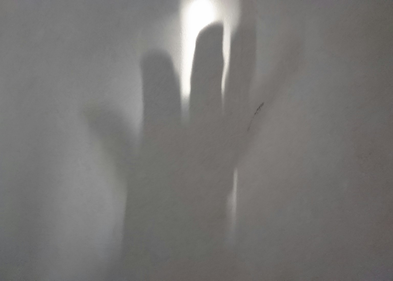 Une ombre de main projetée sur un fond clair