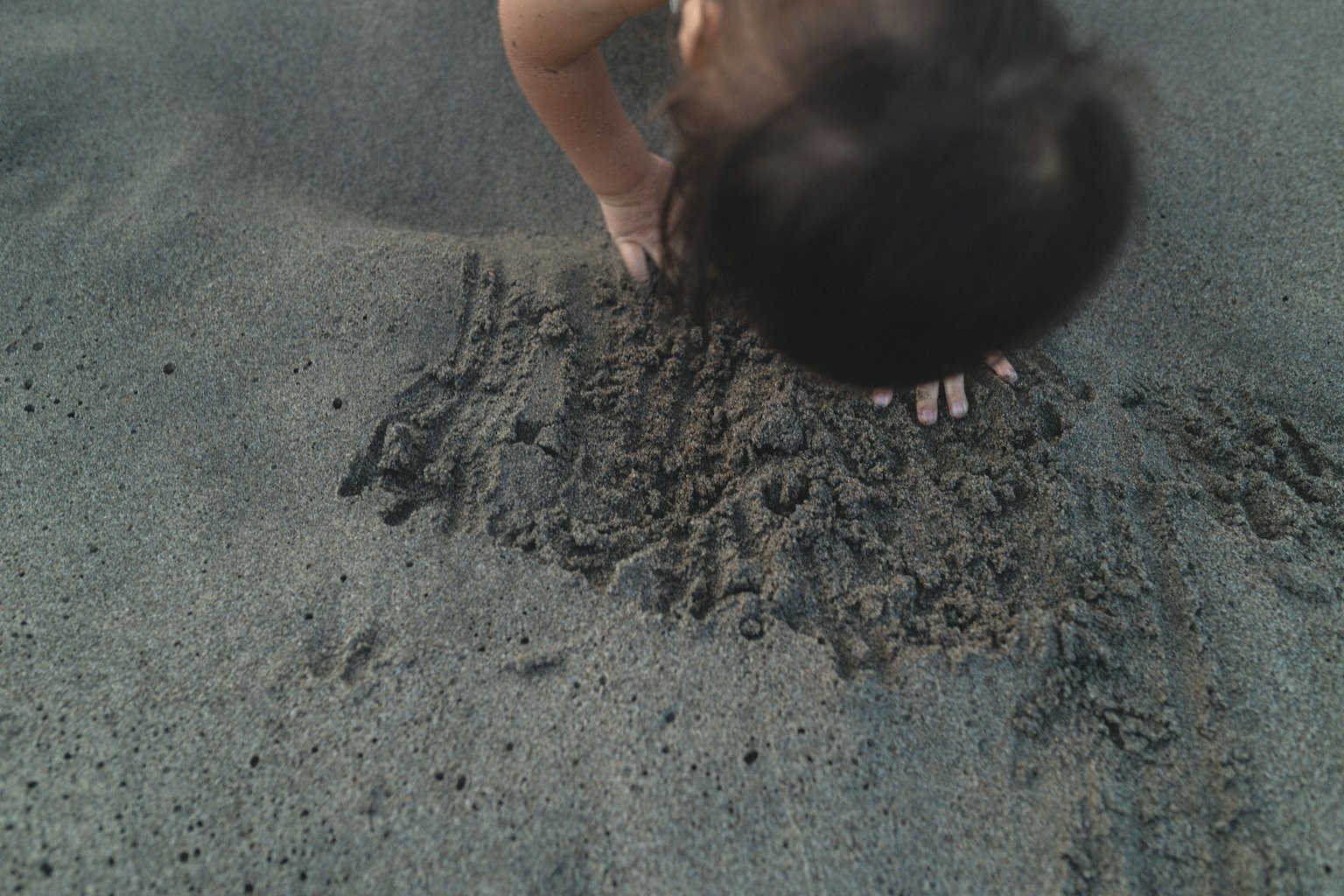 Kind, das im Sand mit den Händen spielt