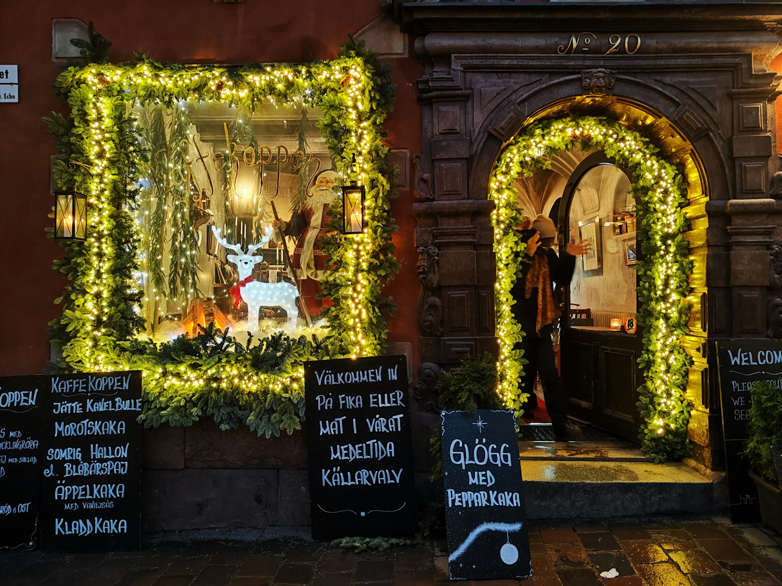 Exterior de un café con ventanas y puerta bellamente decoradas con luces festivas