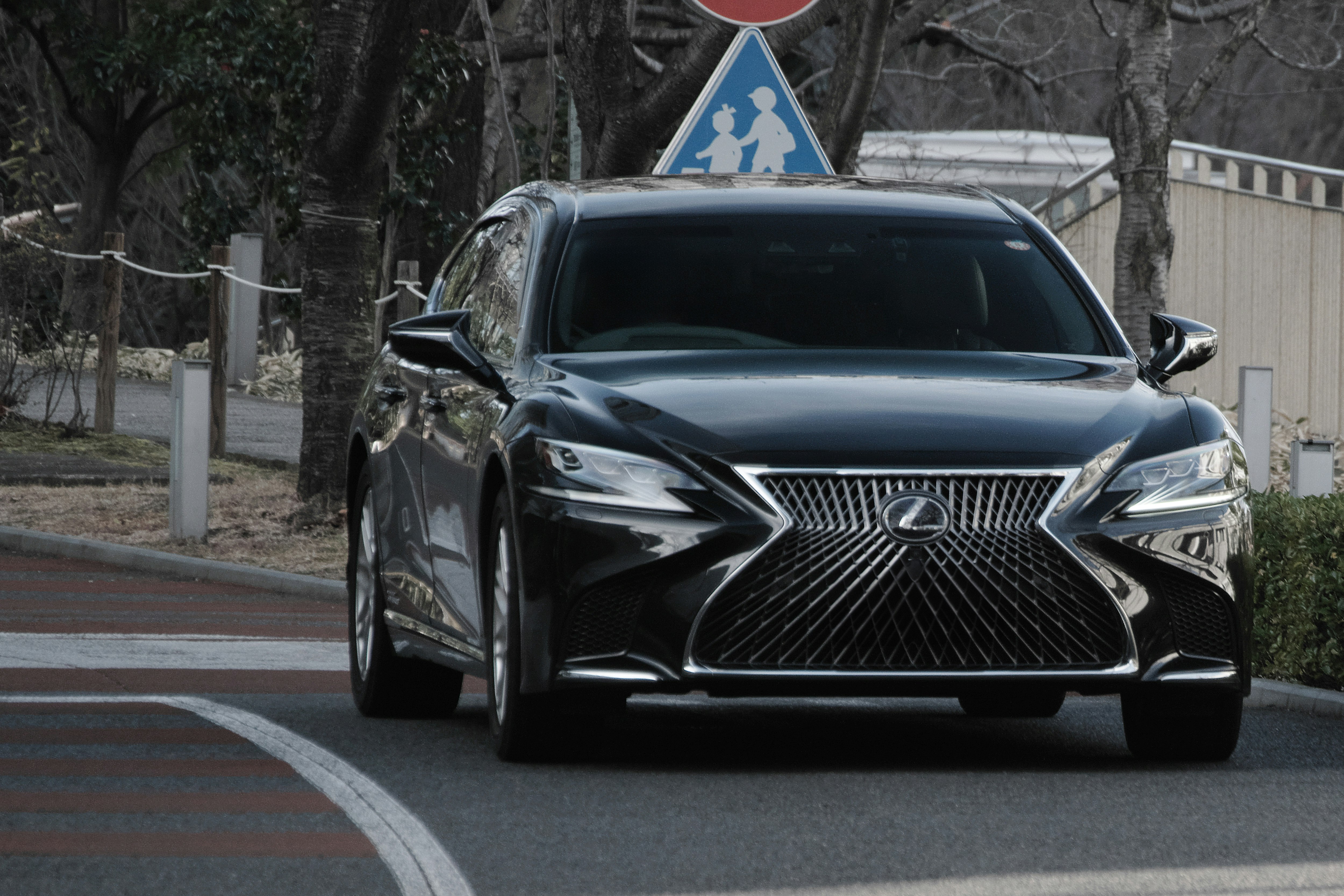 A black Lexus sedan driving on a road
