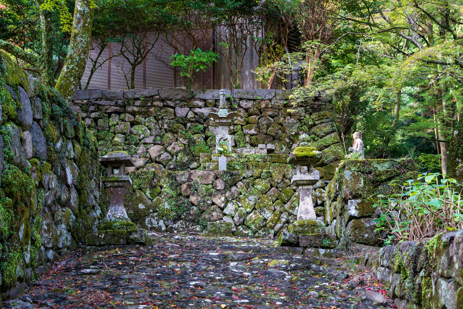 Escena de jardín serena con muros de piedra cubiertos de musgo y faroles de piedra