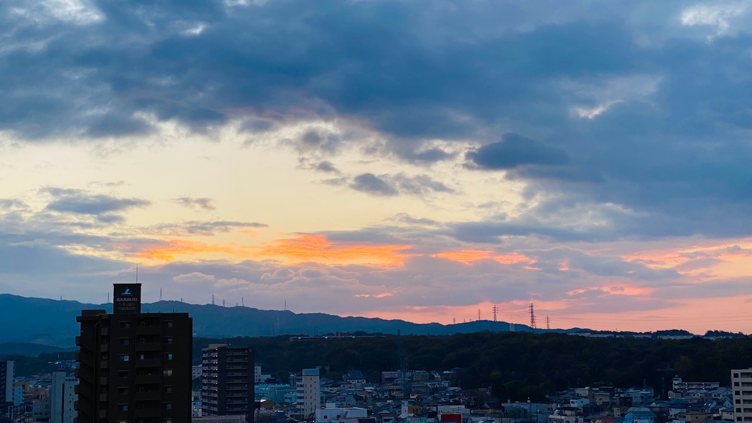 Stadtansicht bei Sonnenuntergang mit buntem Himmel und entfernten Bergen