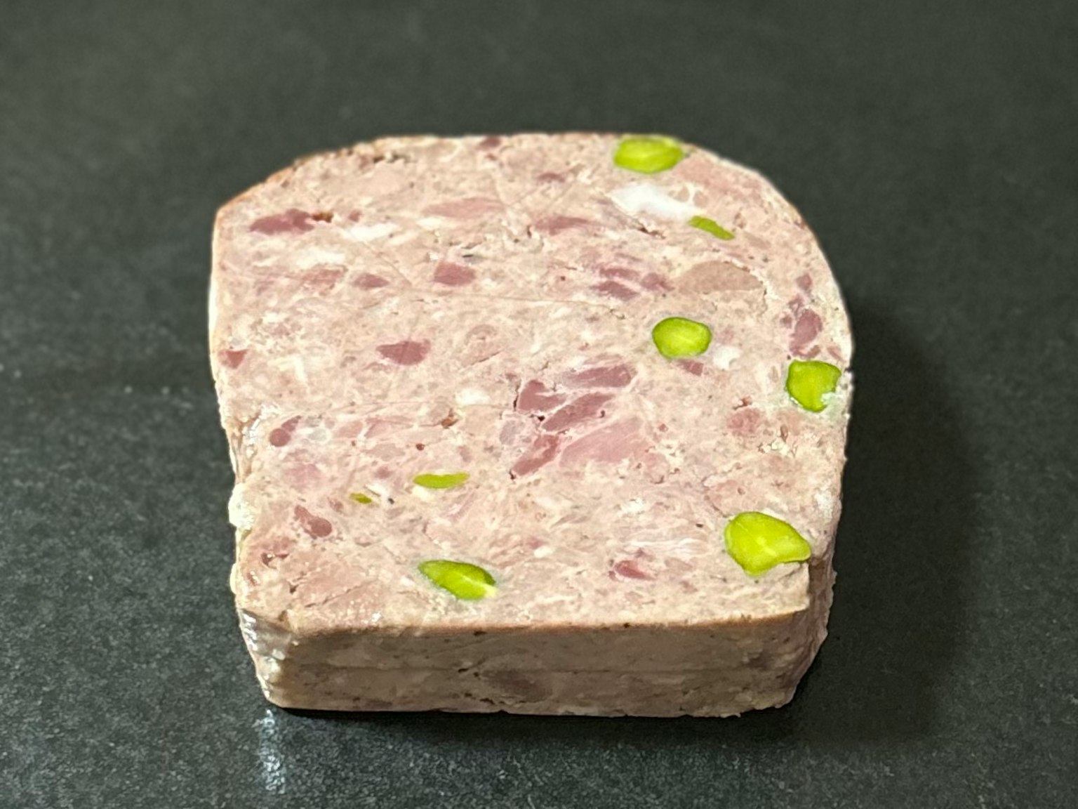 肉类冻品的横截面，上面散落着绿色开心果