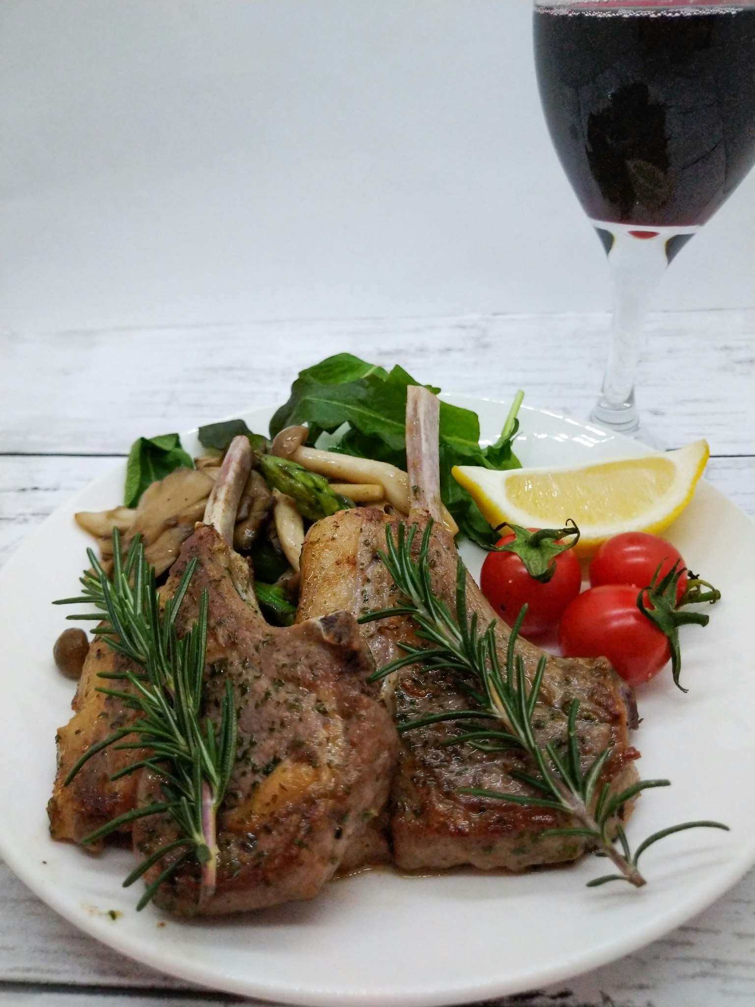 Deliziose costolette d'agnello guarnite con rosmarino servite con insalata e pomodorini