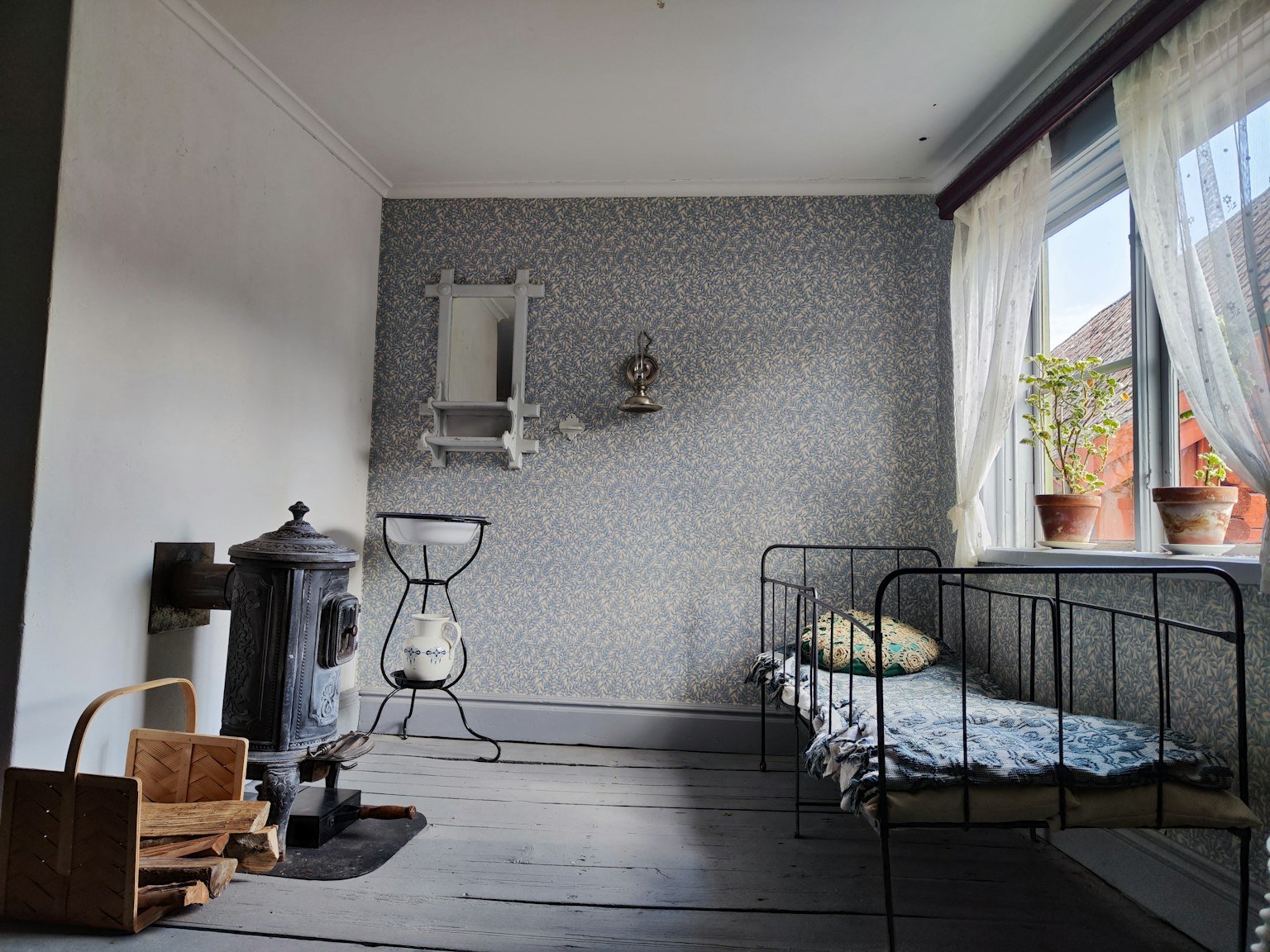 Interior kamar yang nyaman dengan tempat tidur logam dan kompor kecil tirai lembut dan kertas dinding berpattern