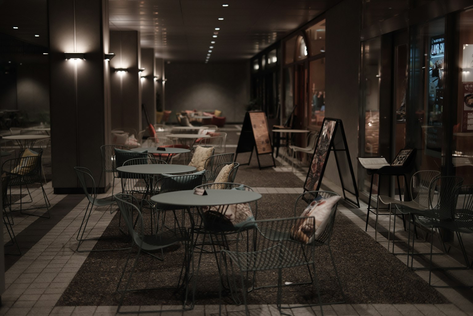 Schwach beleuchtete Café-Terrasse mit Tischen und Stühlen