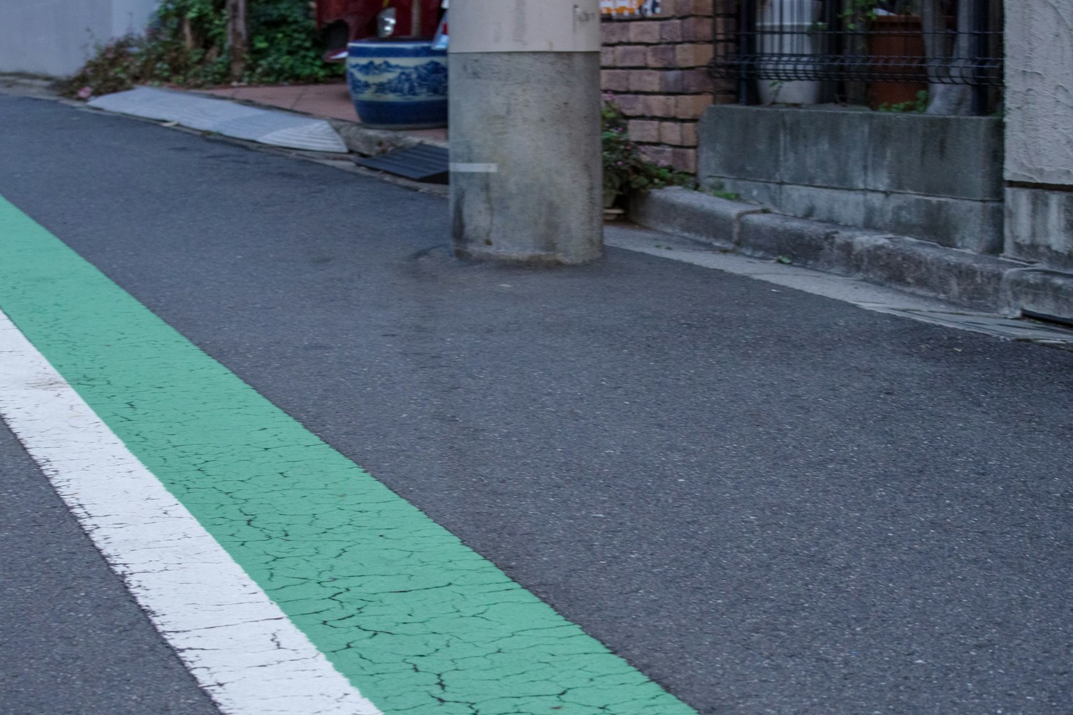 窄街道，带有绿色自行车道和混凝土柱