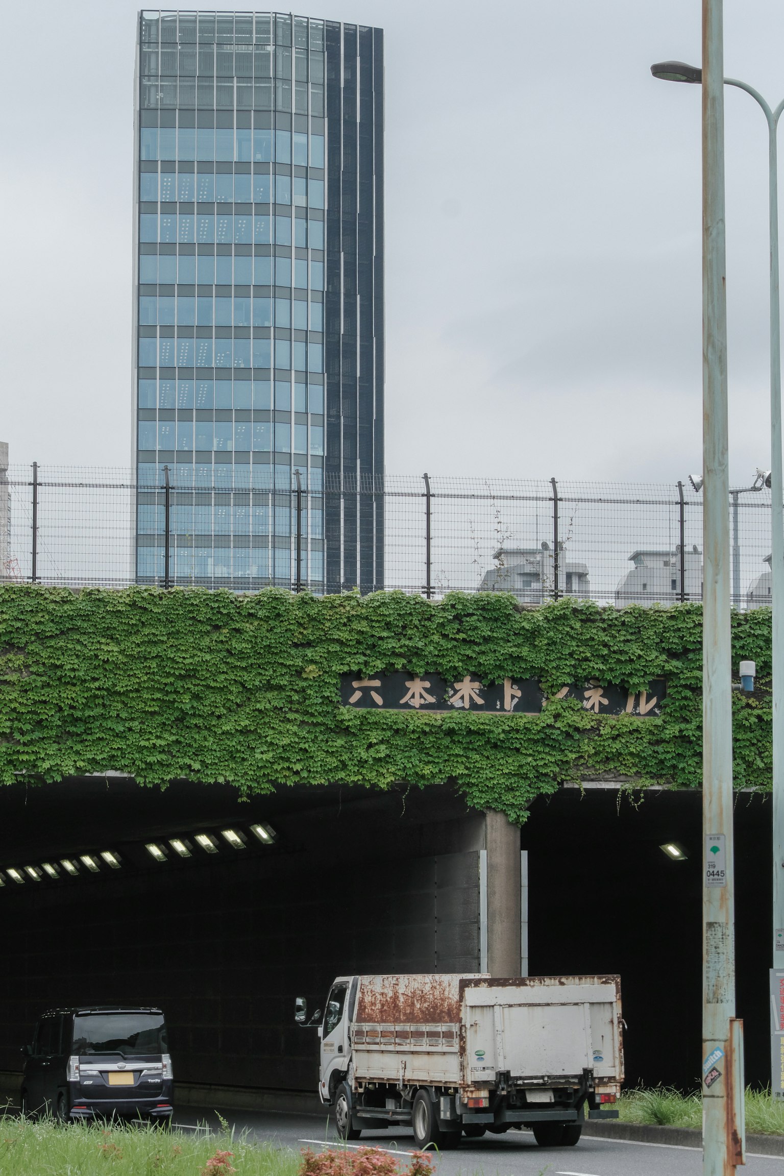 Un edificio alto e l'ingresso di un tunnel coperto di verde sono visibili