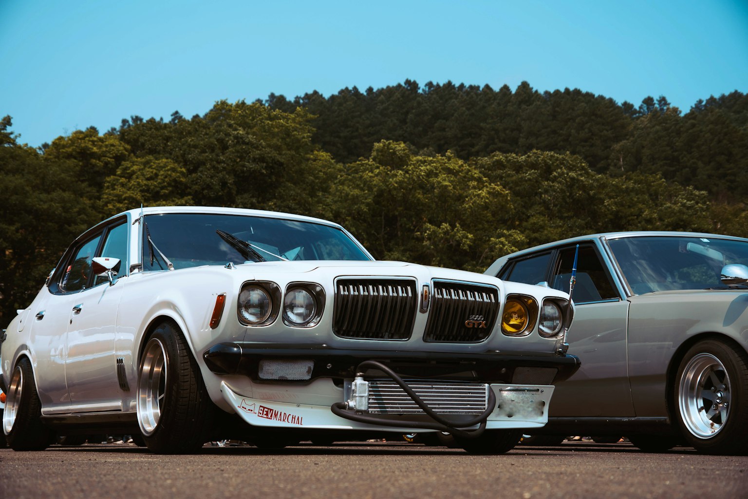 Angepasster weißer Sportwagen und silbernes Fahrzeug nebeneinander geparkt