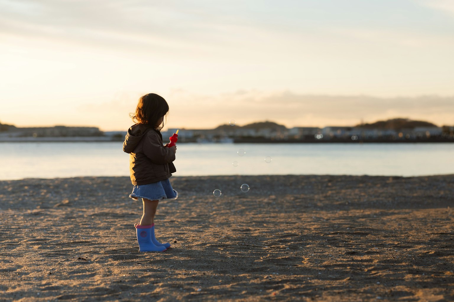 Siluet anak bermain di pantai saat matahari terbenam
