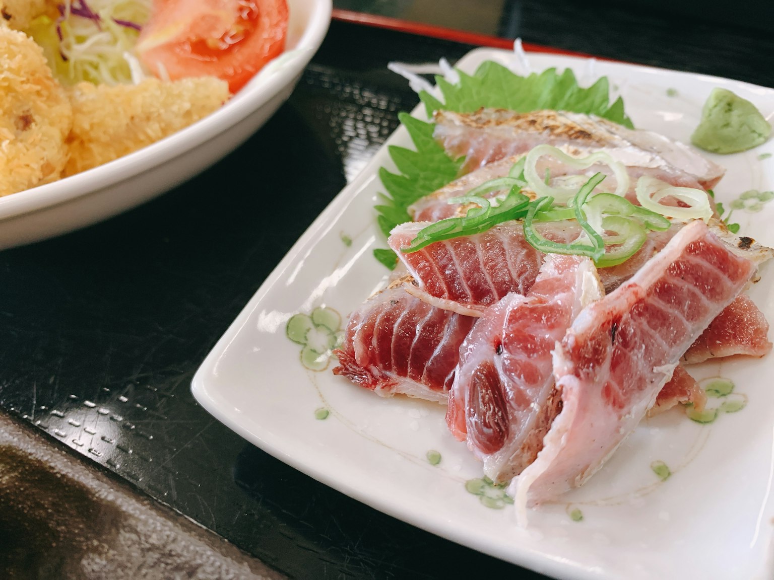 Plate of fresh sashimi with green onions and garnishes