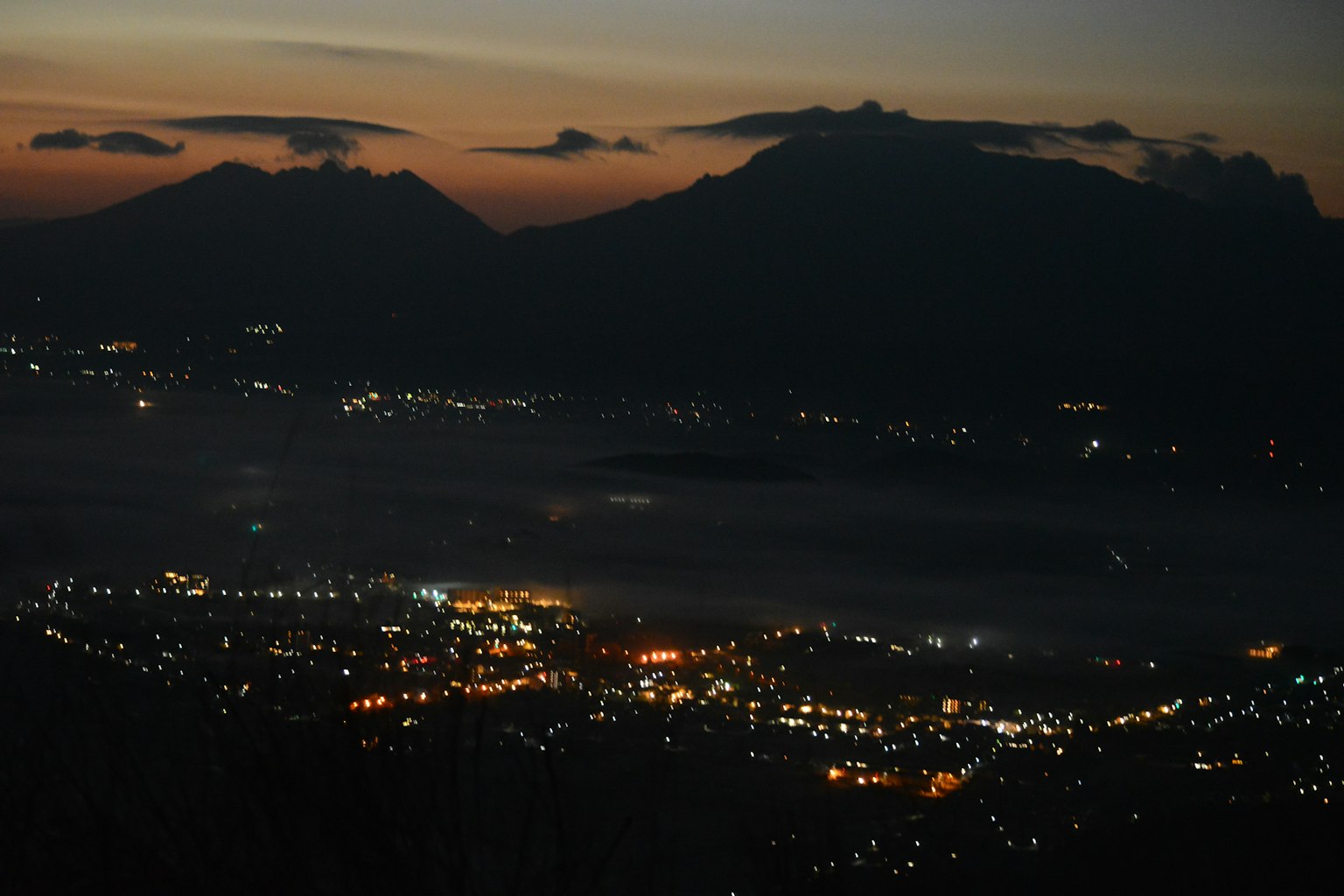 Vista panoramica di montagne e luci della città al crepuscolo