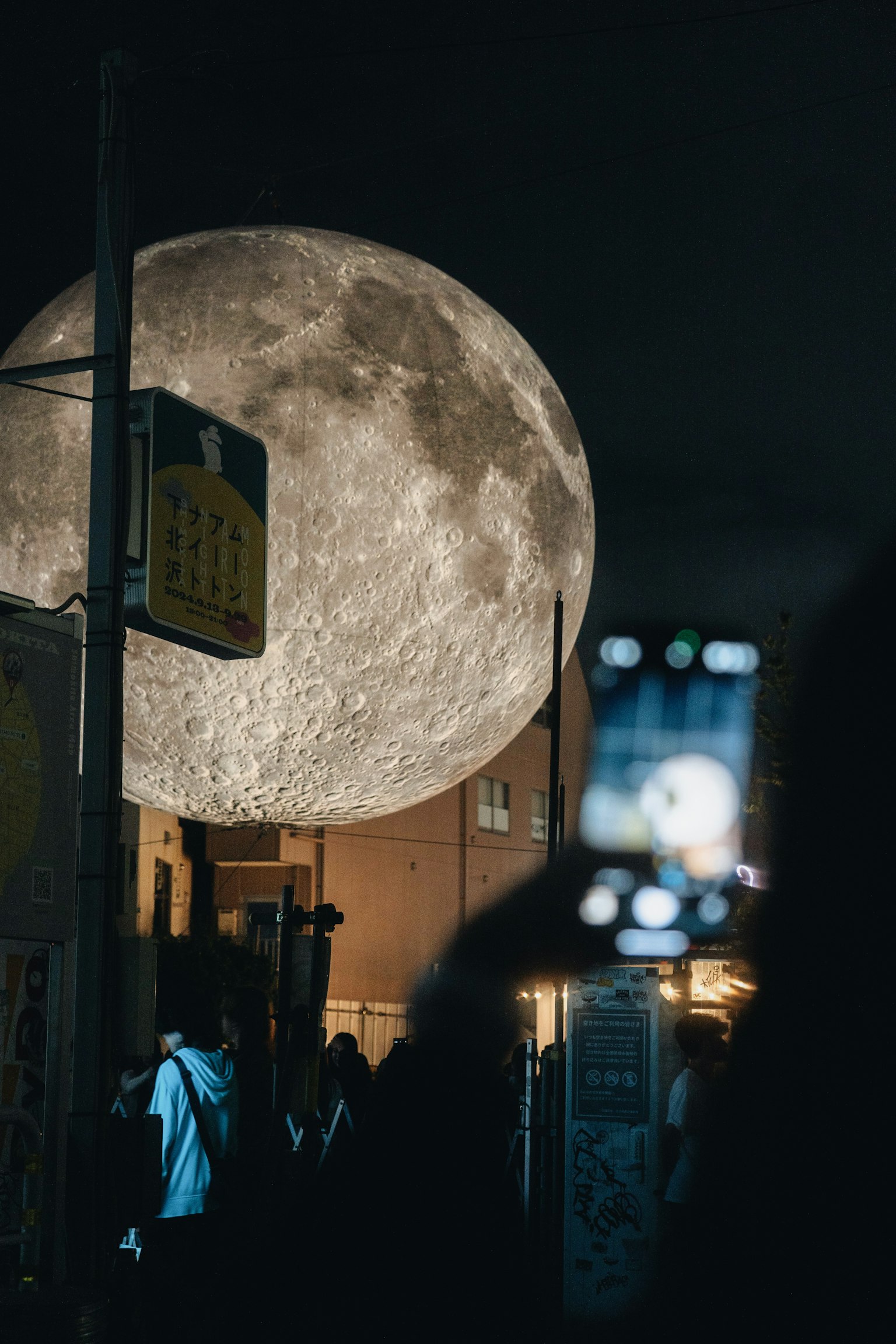 Une grande pleine lune dans le ciel nocturne avec des gens rassemblés en dessous