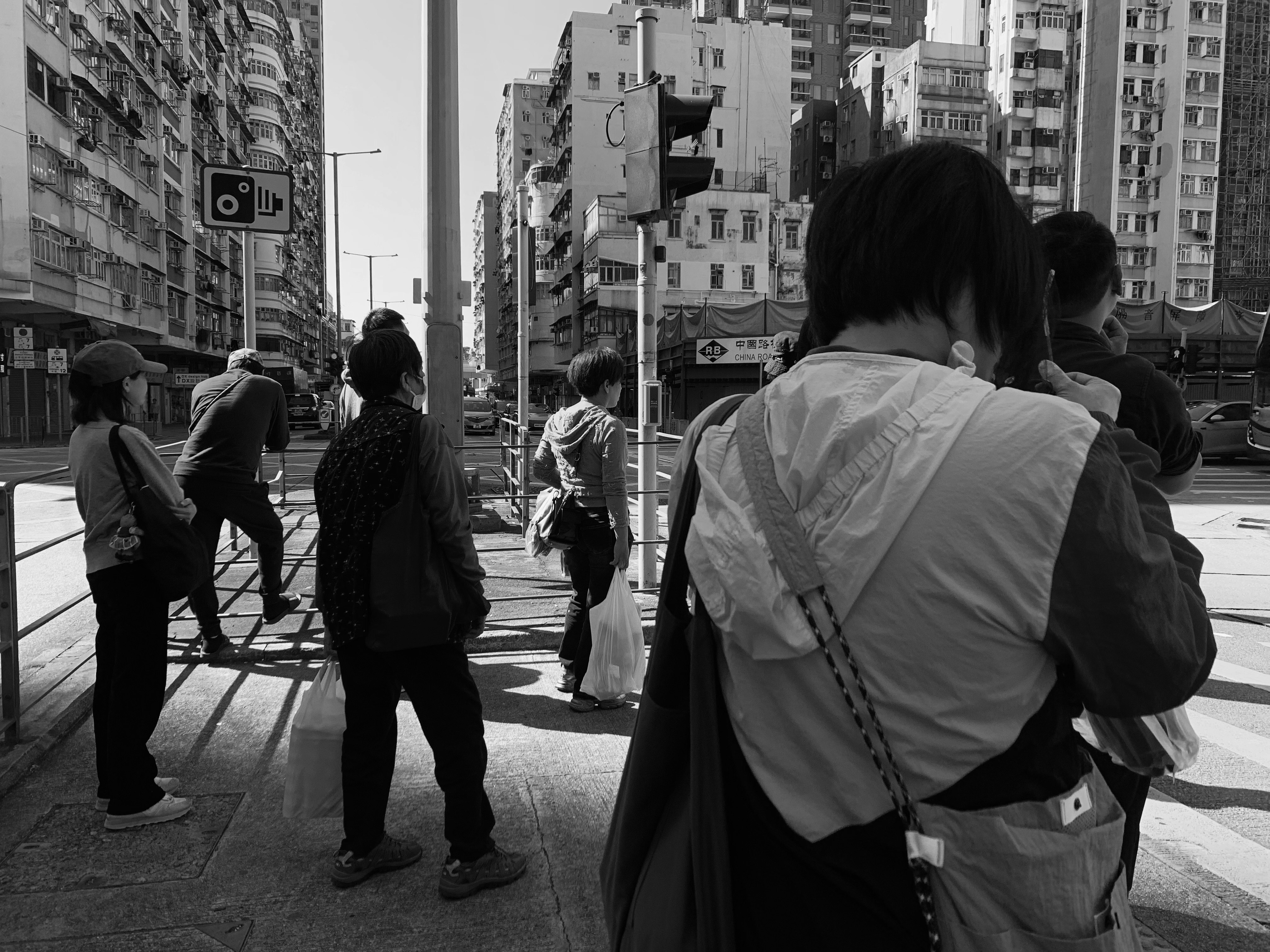 人々が街角で待っているモノクロの風景 建物が立ち並ぶ背景