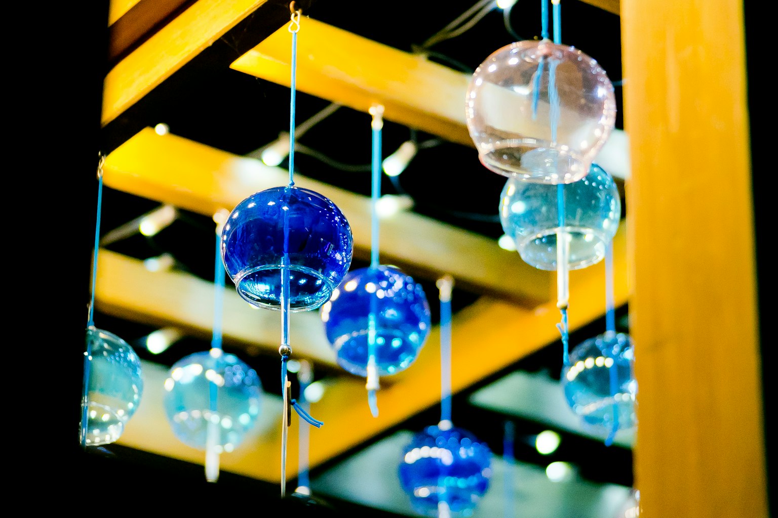 Esferas de vidrio azules y transparentes colgando de una estructura de madera
