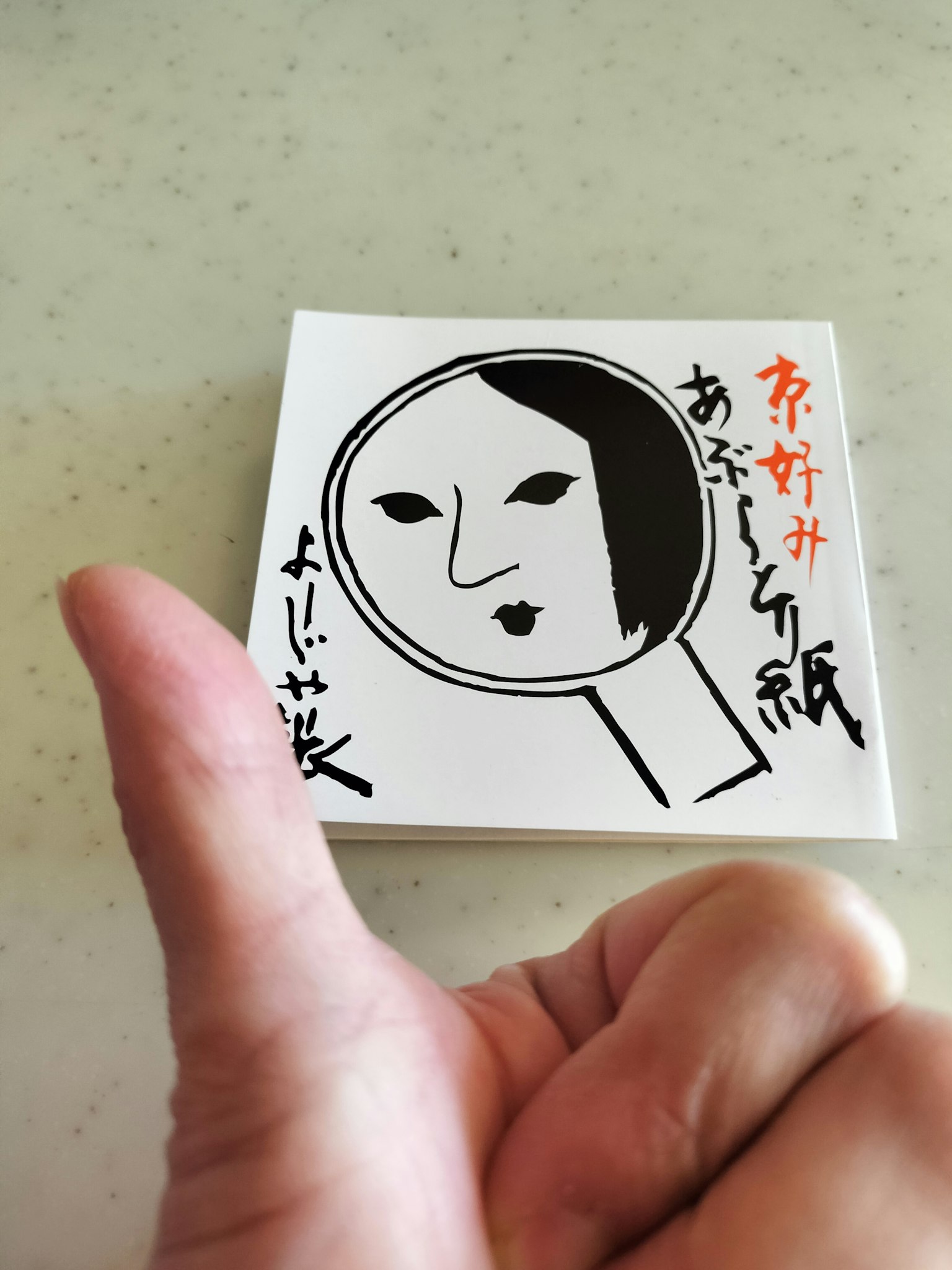 手中持有的白色卡片，上面有一個臉的插圖和放大鏡