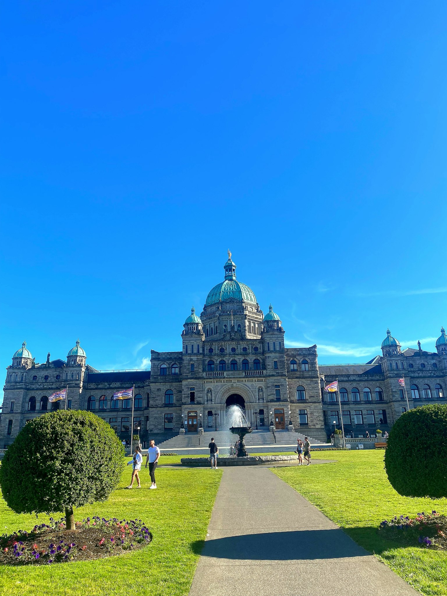 Grandioso exterior de la Legislatura de Columbia Británica bajo un cielo azul claro con jardines bien cuidados