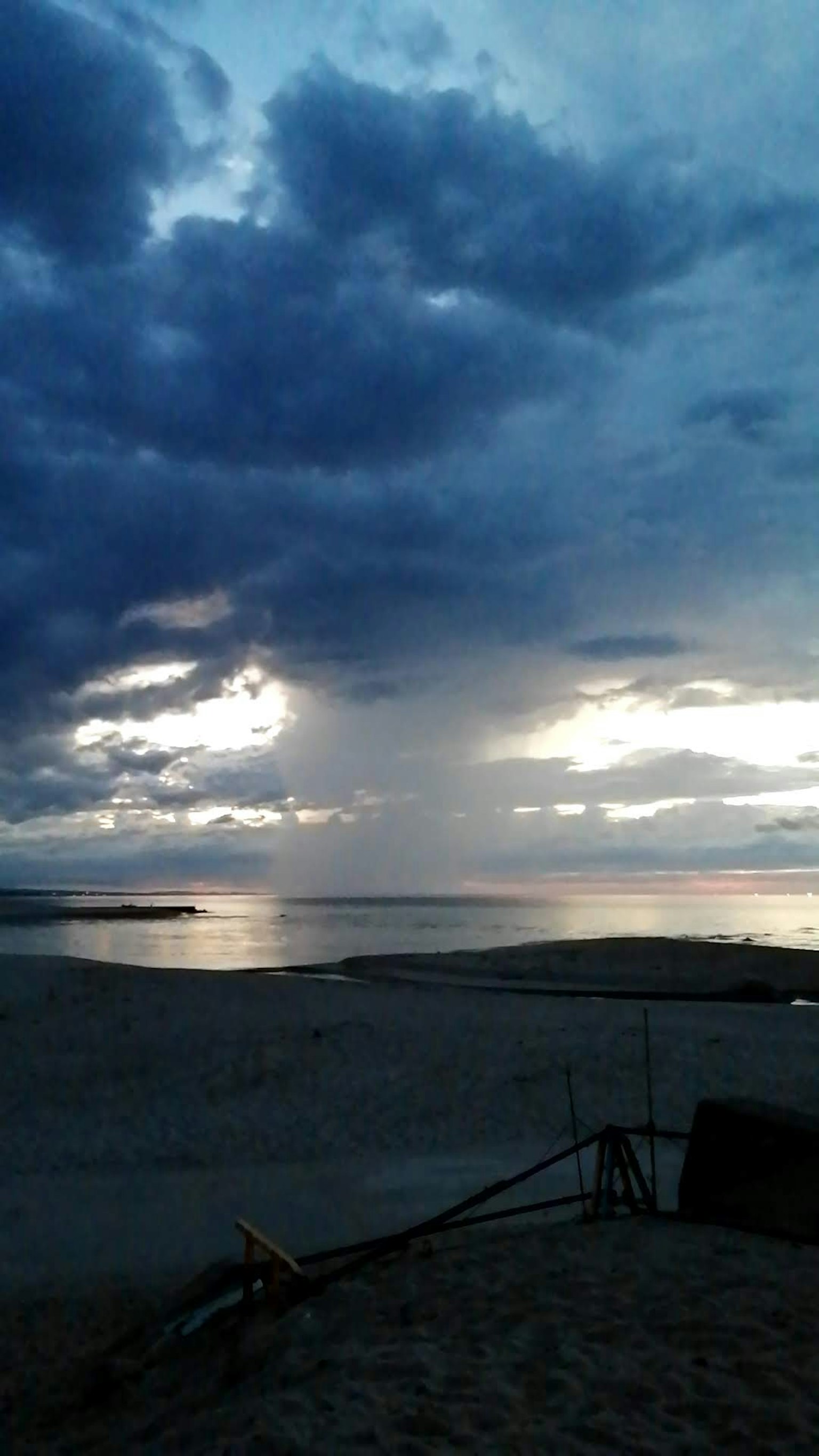 Scena di spiaggia con nuvole scure e oceano riflettente