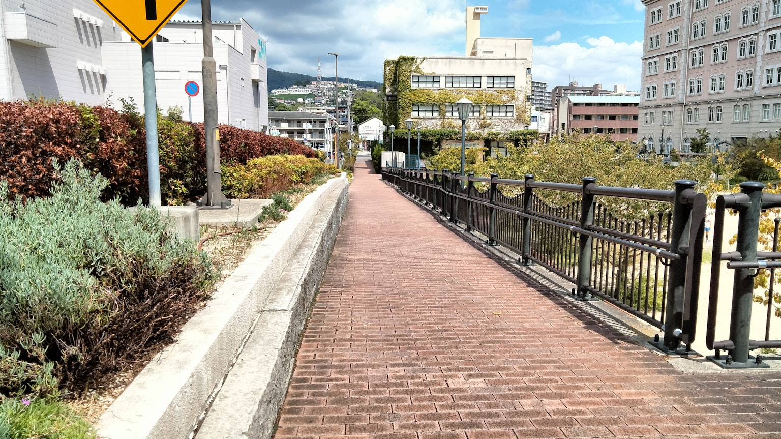 Paved walkway with a black iron fence and urban buildings