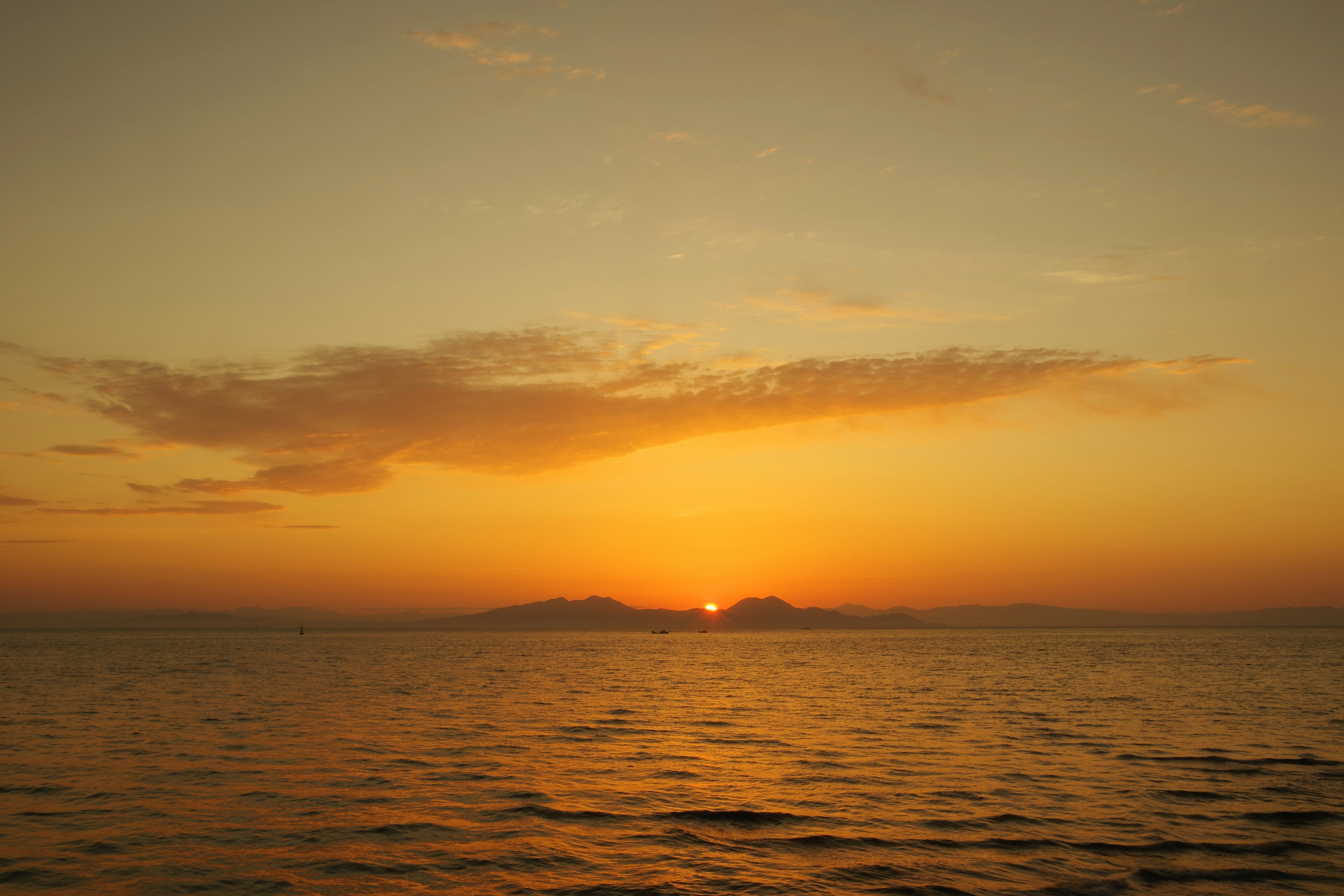 水平線に沈む夕日と穏やかな海面の風景