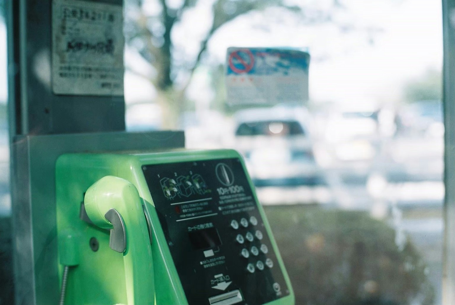 Intérieur d'une cabine téléphonique verte avec un arrière-plan flou