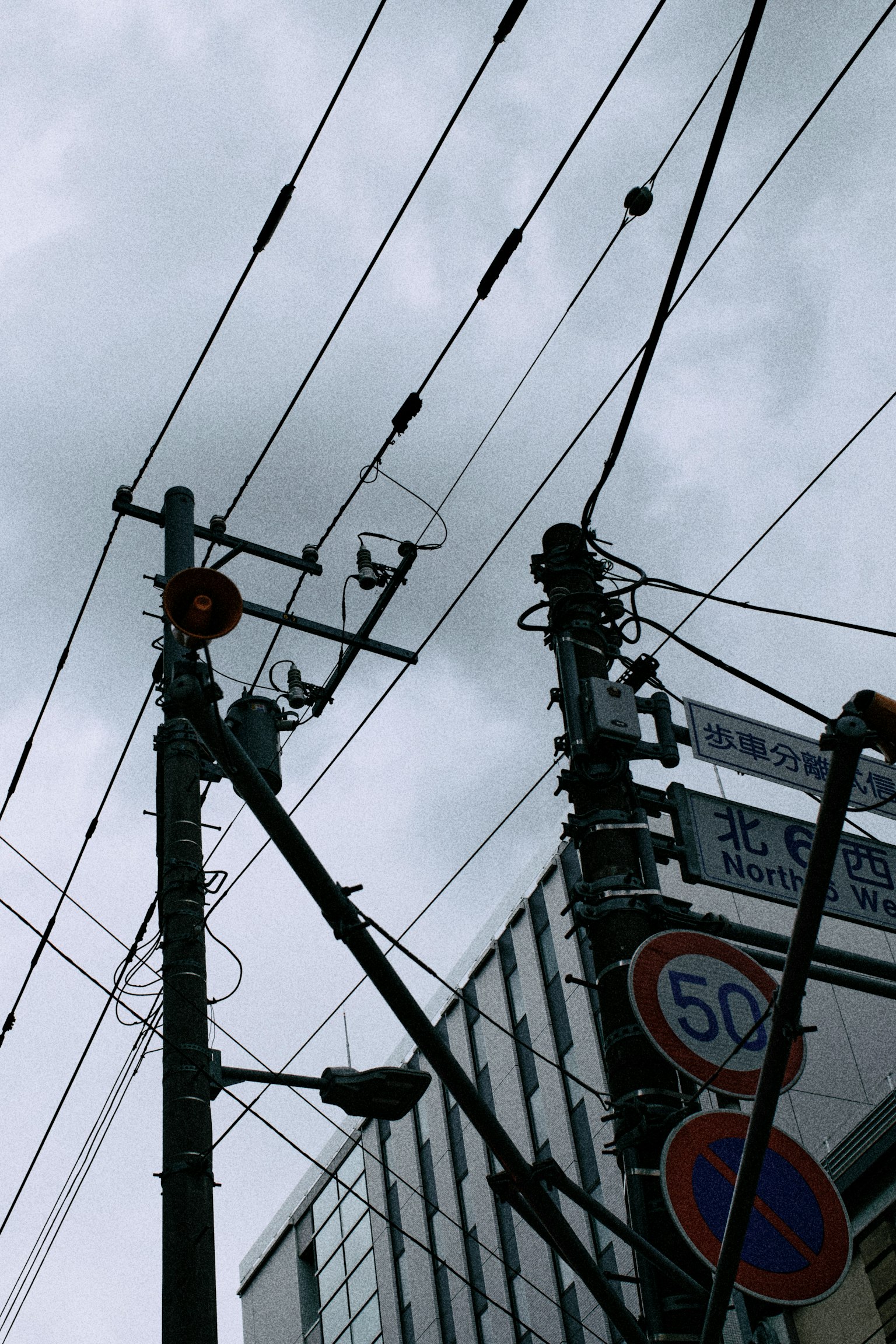 Vista de intersección de postes y cables bajo un cielo nublado