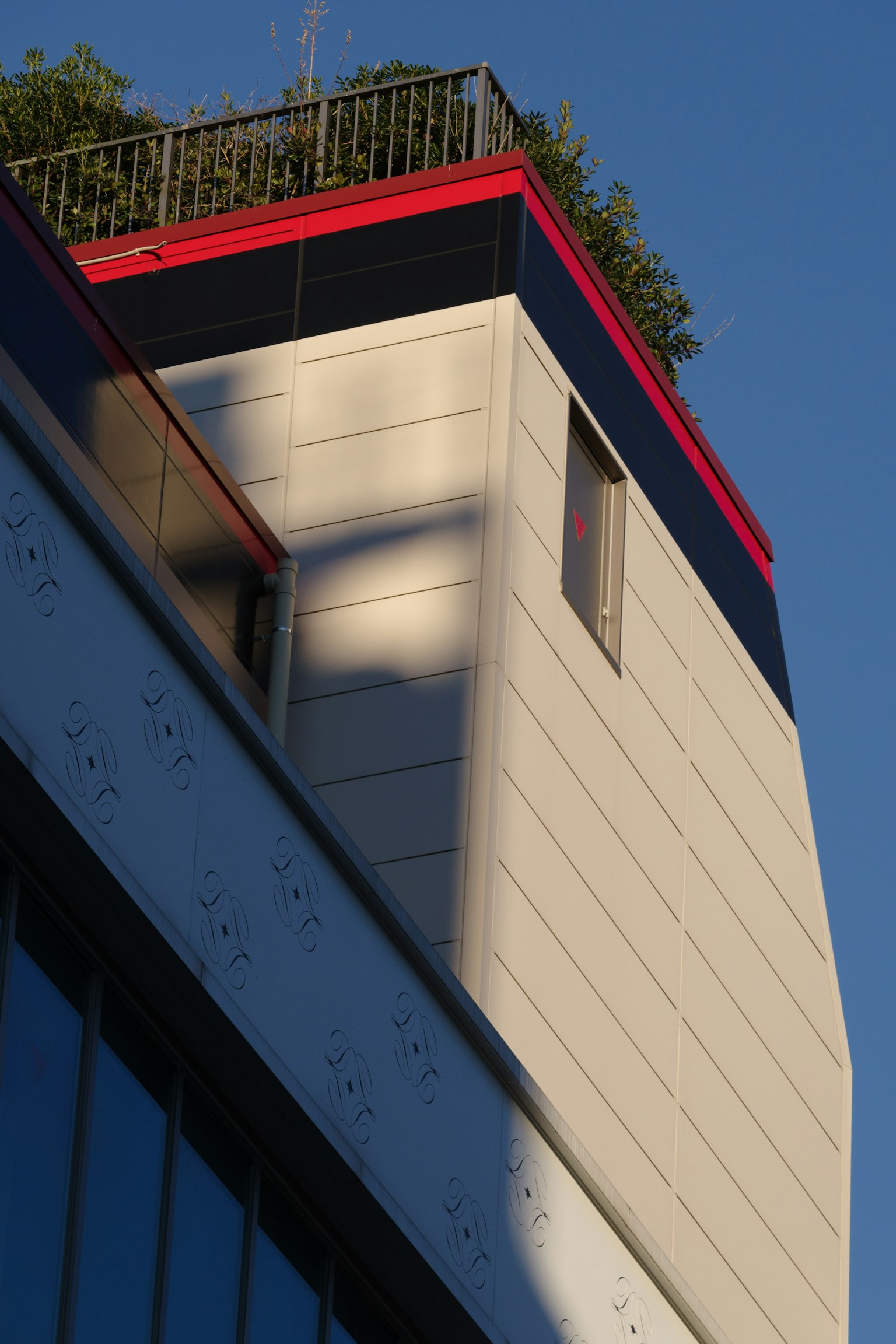 Coin d'un bâtiment moderne avec une bordure rouge sous un ciel bleu