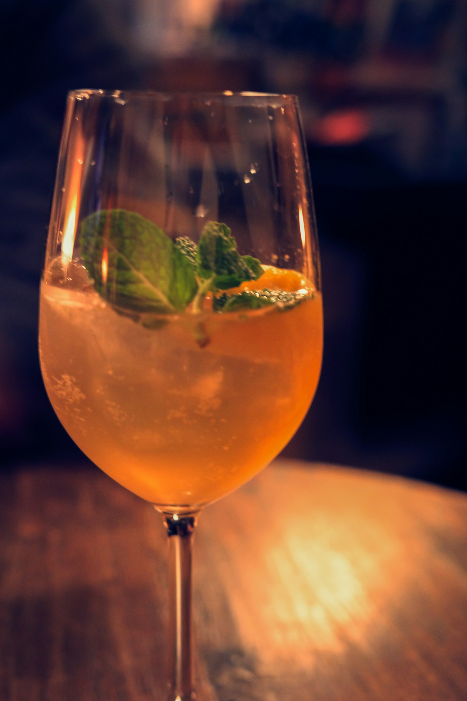 Cocktail arancione guarnito con foglie di menta e fette d'arancia in un bicchiere