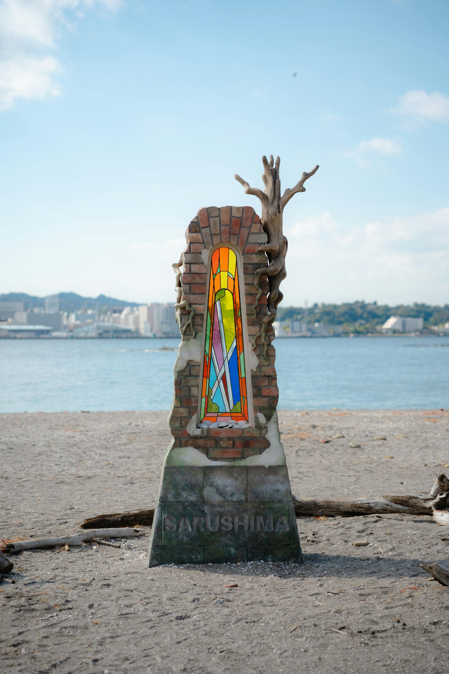Bunte Glasmalerei-Skulptur am Strand mit umliegender Landschaft