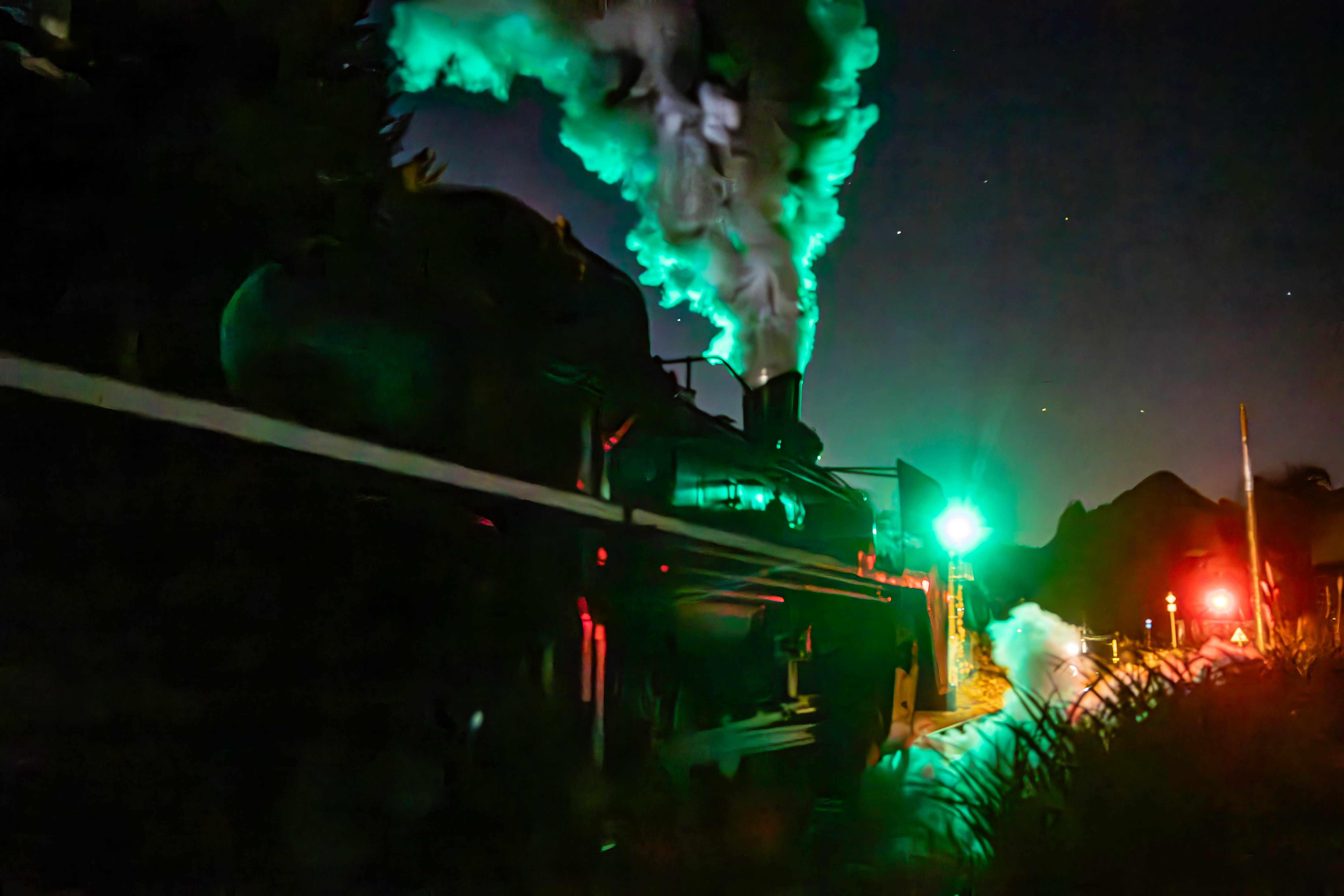 夜の工場地帯を照らす緑と赤の発光