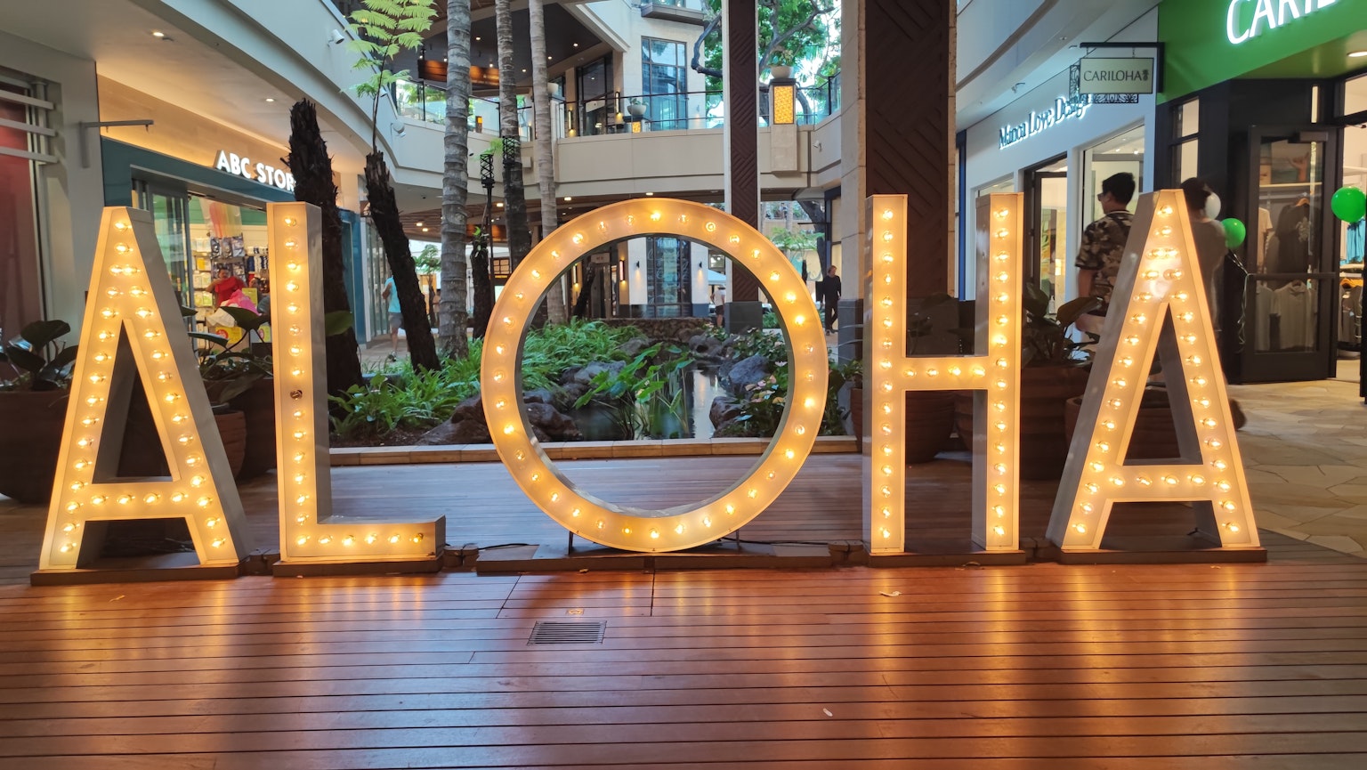 Helle Leuchtschrift mit dem Wort "ALOHA" im Inneren eines Einkaufszentrums