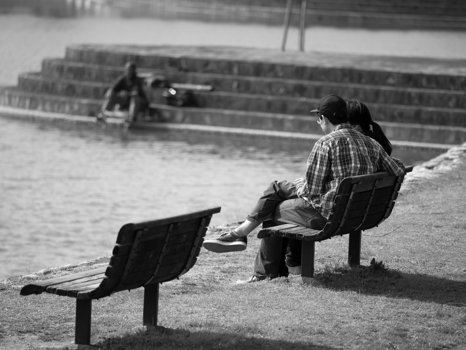 Pasangan duduk di bangku taman di tepi air