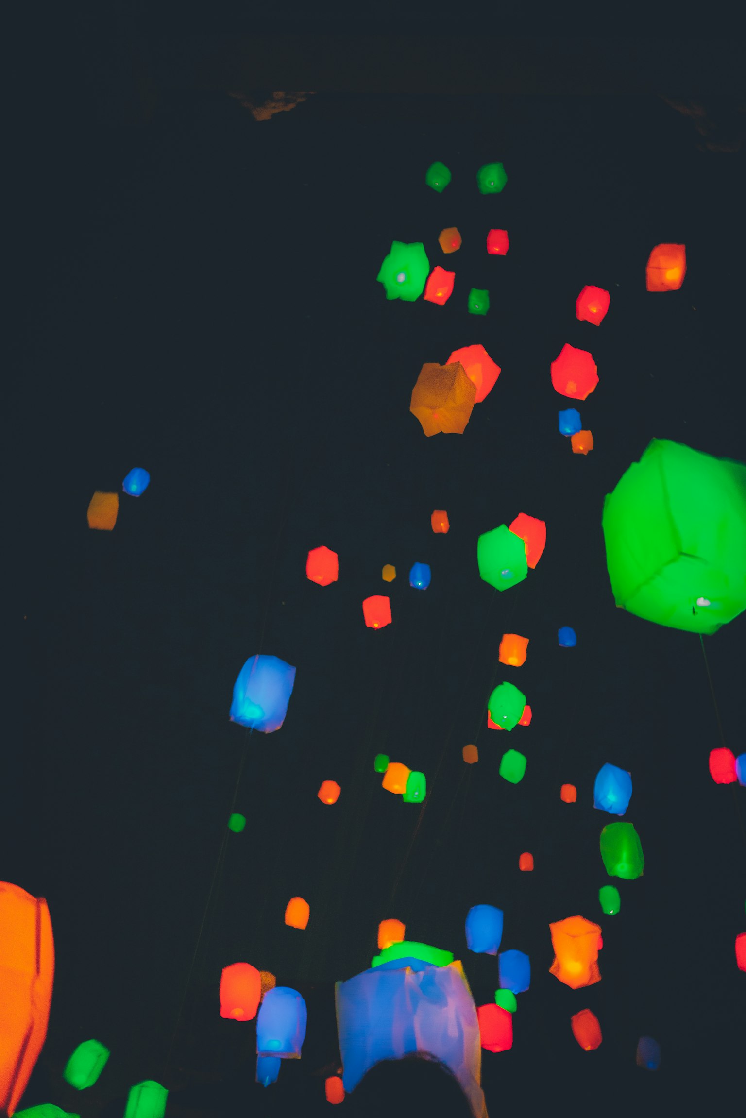 Des lanternes colorées flottant sur un fond sombre