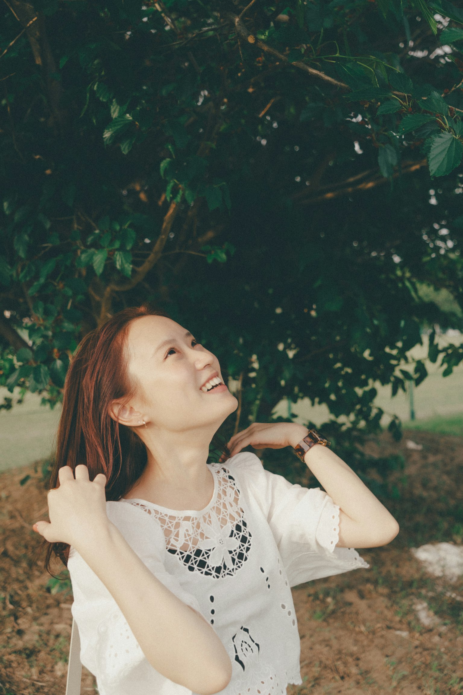 Portrait d'une femme souriante sous un arbre vert