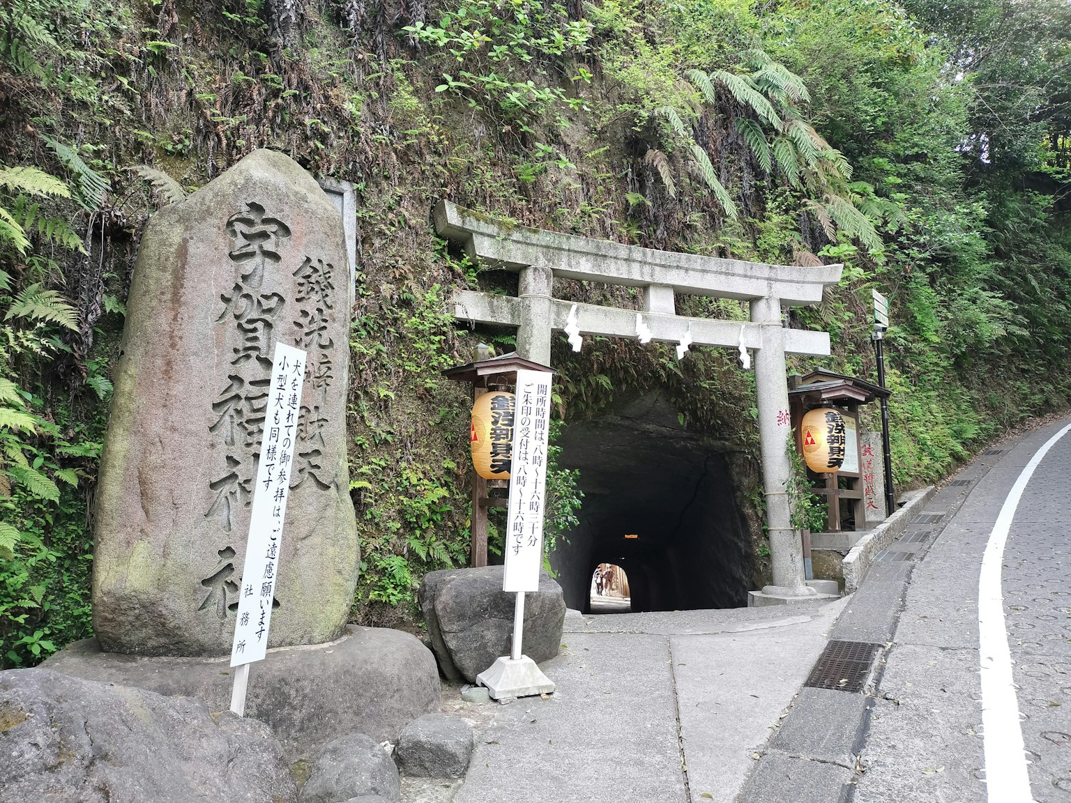 Entrée de tunnel dans les montagnes avec un torii et un monument en pierre