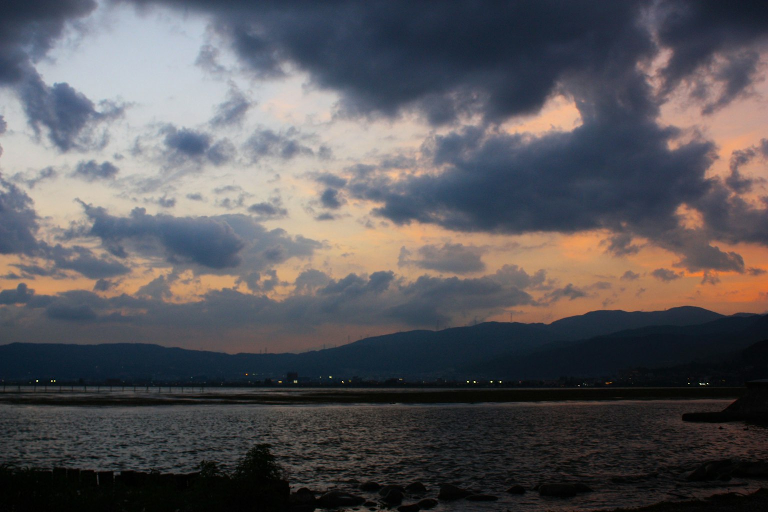 Vue au crépuscule de la mer et des montagnes avec un ciel en dégradé orange et bleu