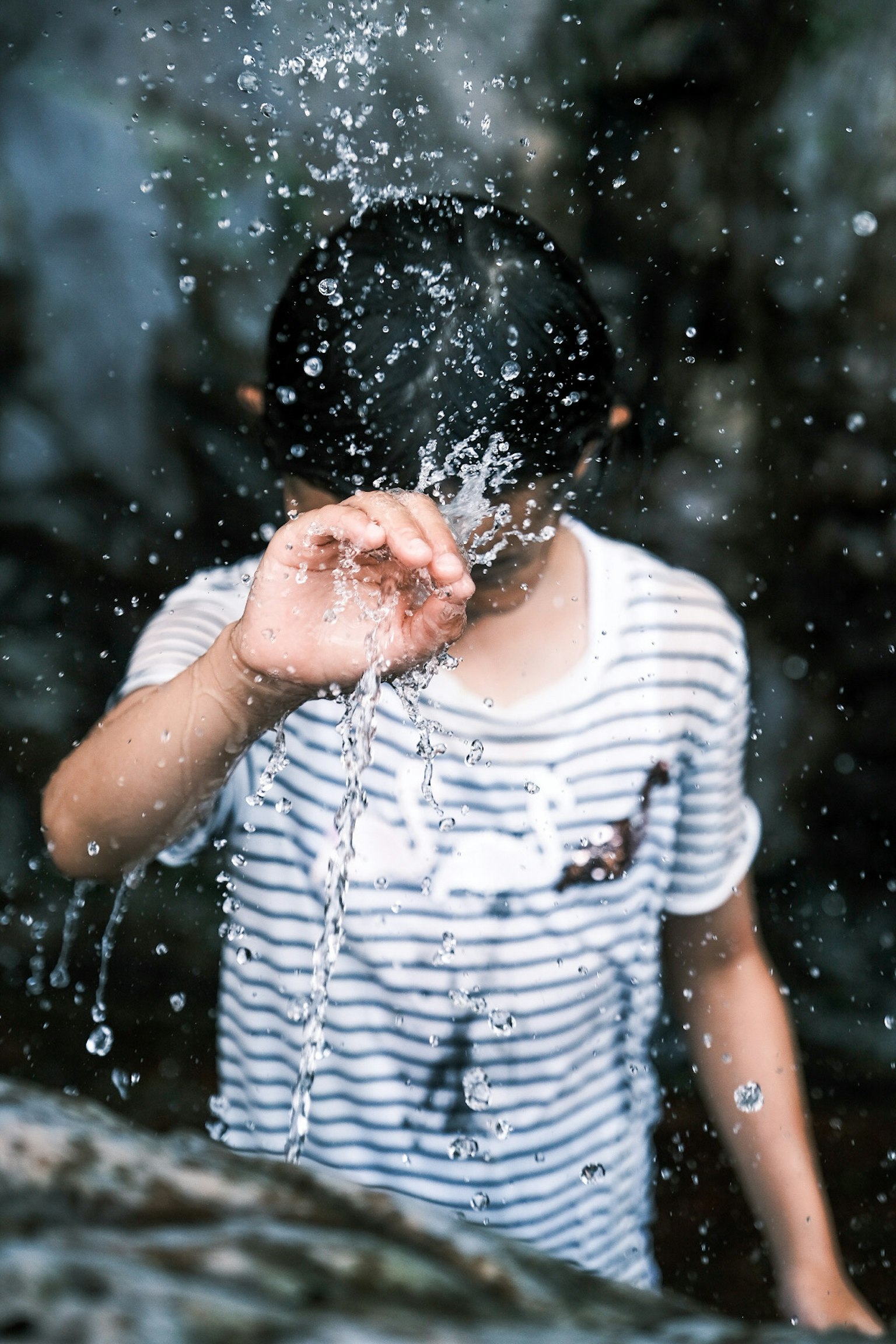 Niño con camiseta a rayas salpicando agua