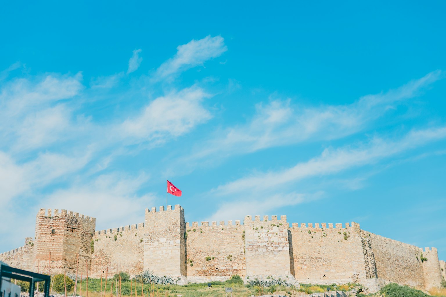 Mura del castello sotto un cielo blu con una bandiera turca