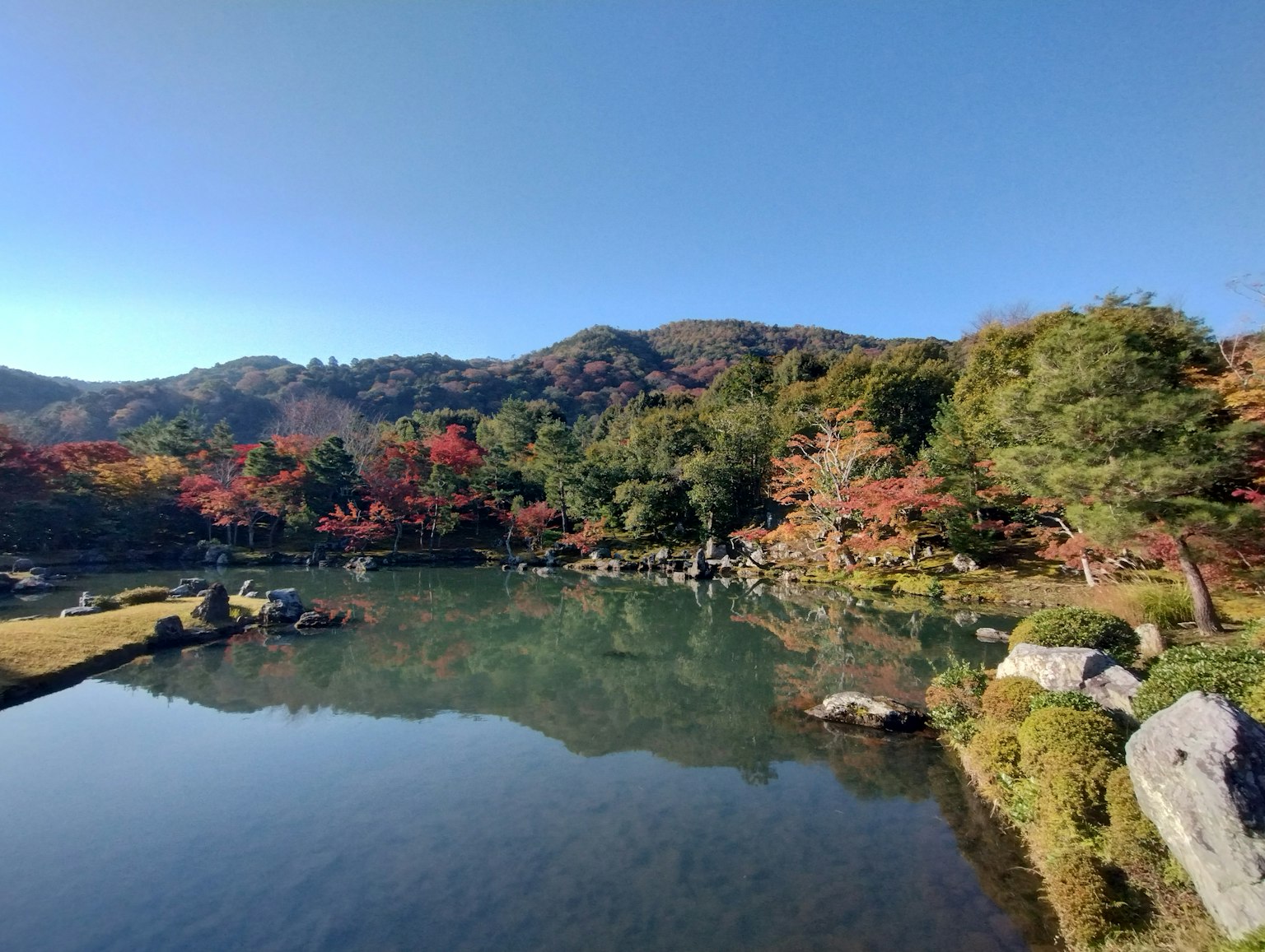 Scenic autumn landscape featuring a tranquil pond and mountains
