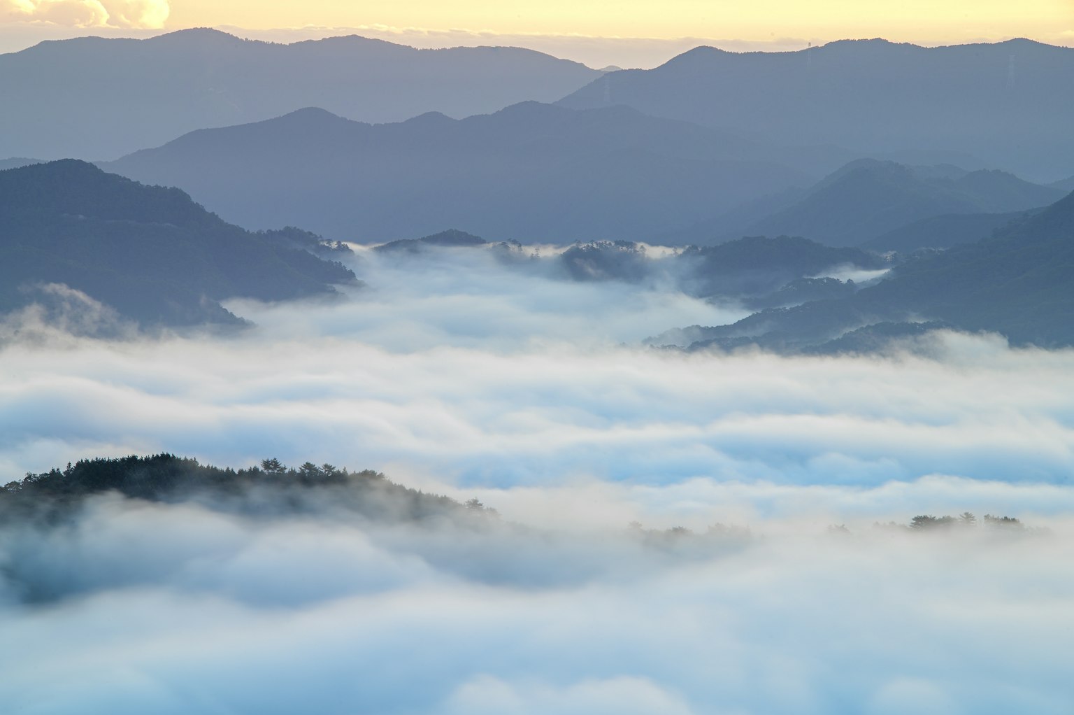 Paesaggio montano avvolto nella nebbia con un cielo morbido al tramonto