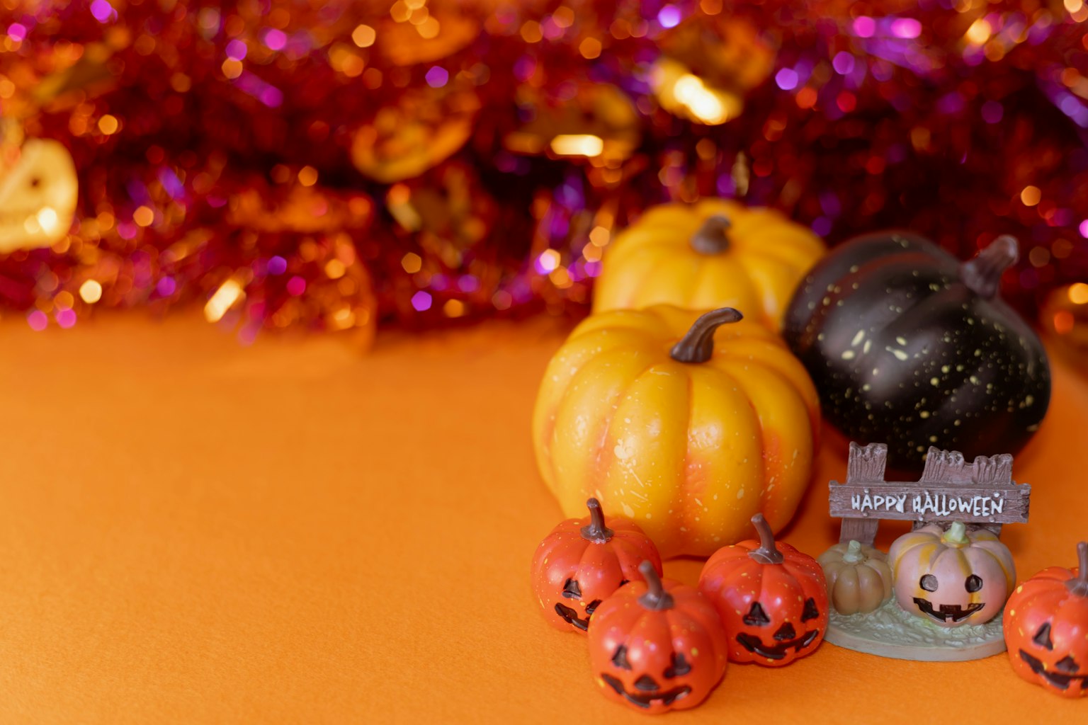 Bunte Halloween-Dekorationen mit kleinen Kürbissen auf orangefarbenem Hintergrund