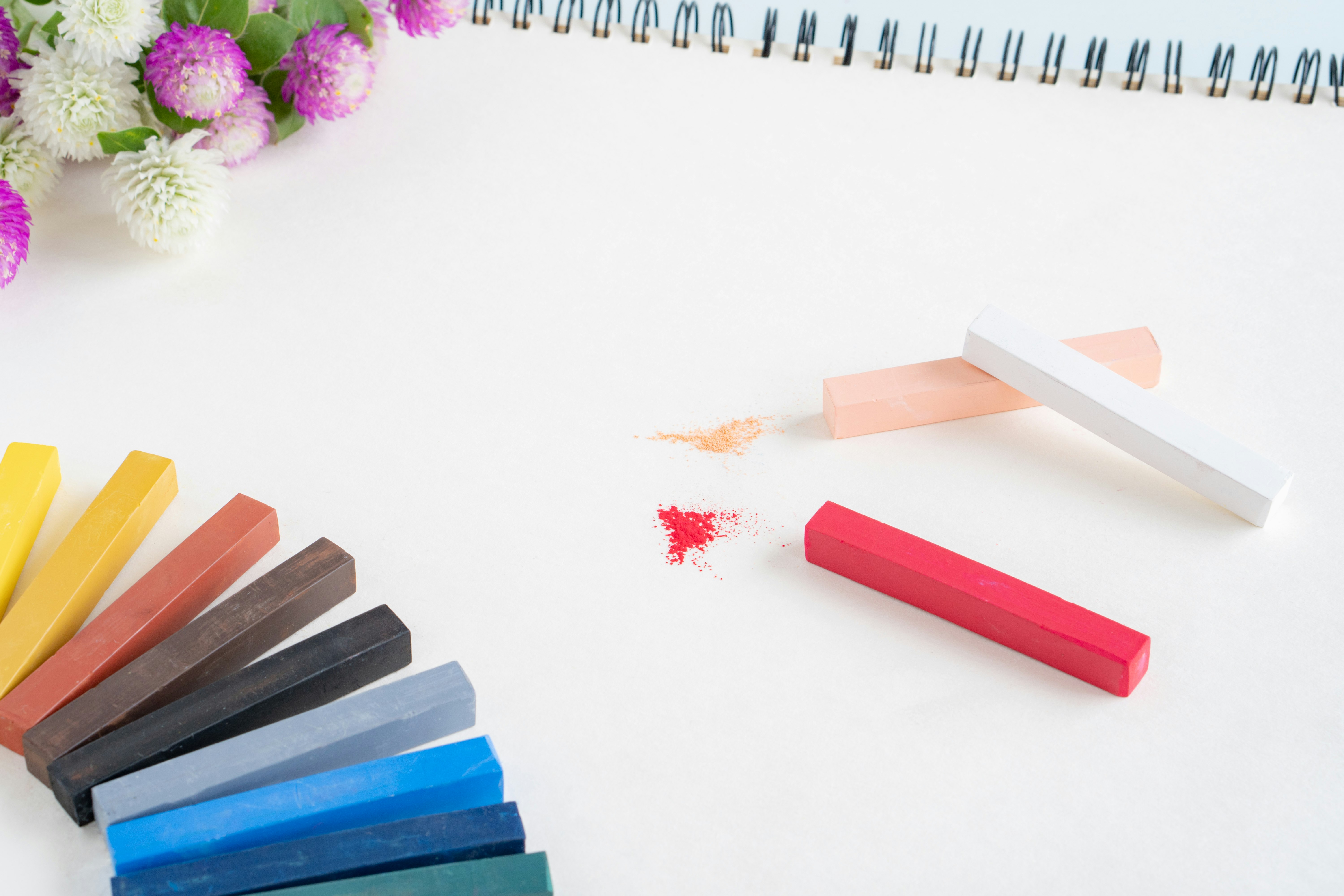 Flat lay of colorful chalk sticks and an eraser on a white background