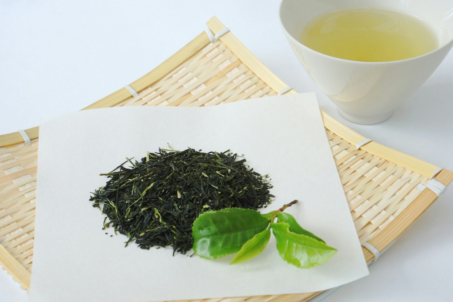 Scène avec des feuilles de thé vert et une tasse de thé infusé