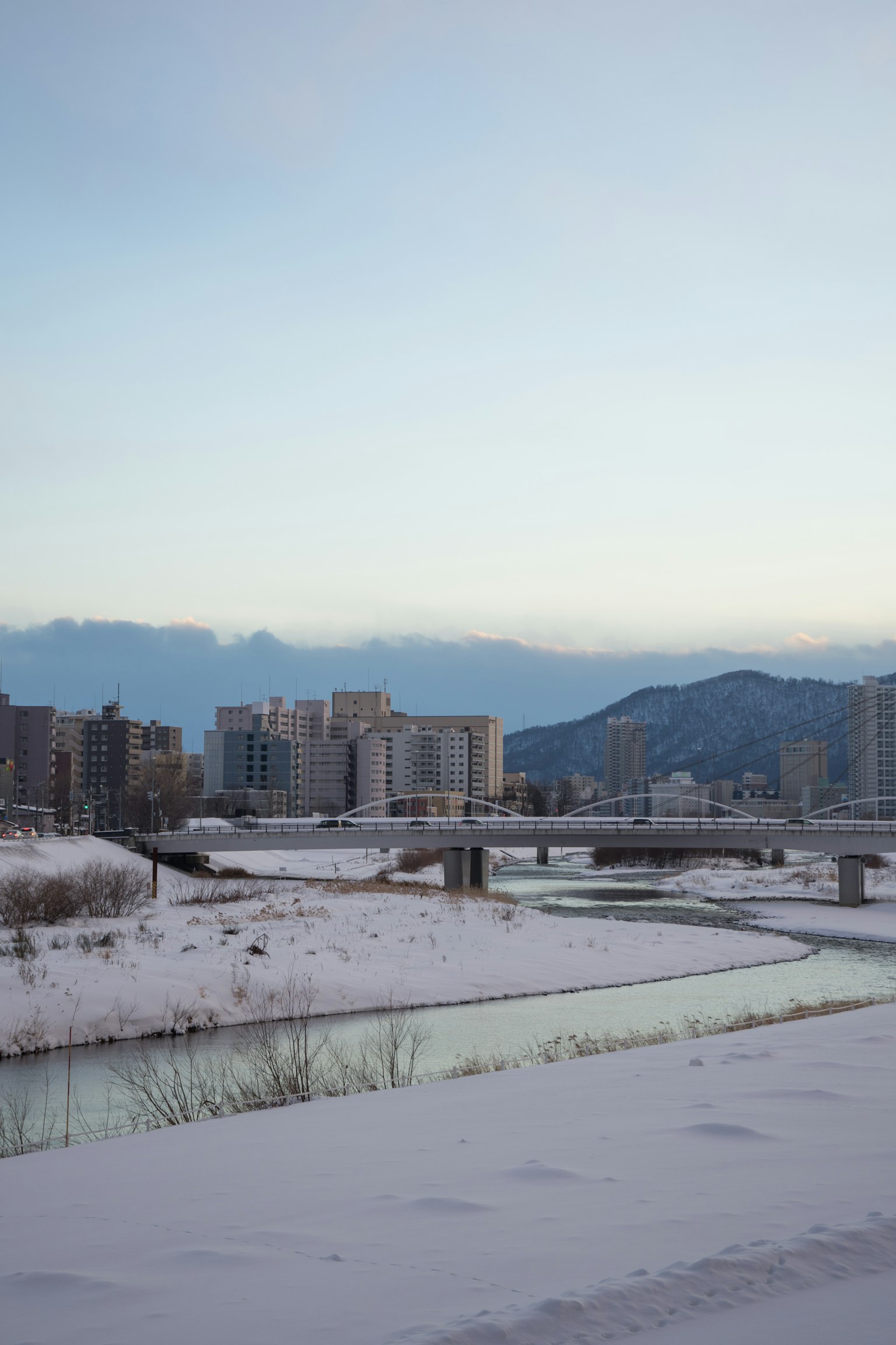 Sungai yang tertutup salju dan pemandangan kota dengan suasana musim dingin yang tenang
