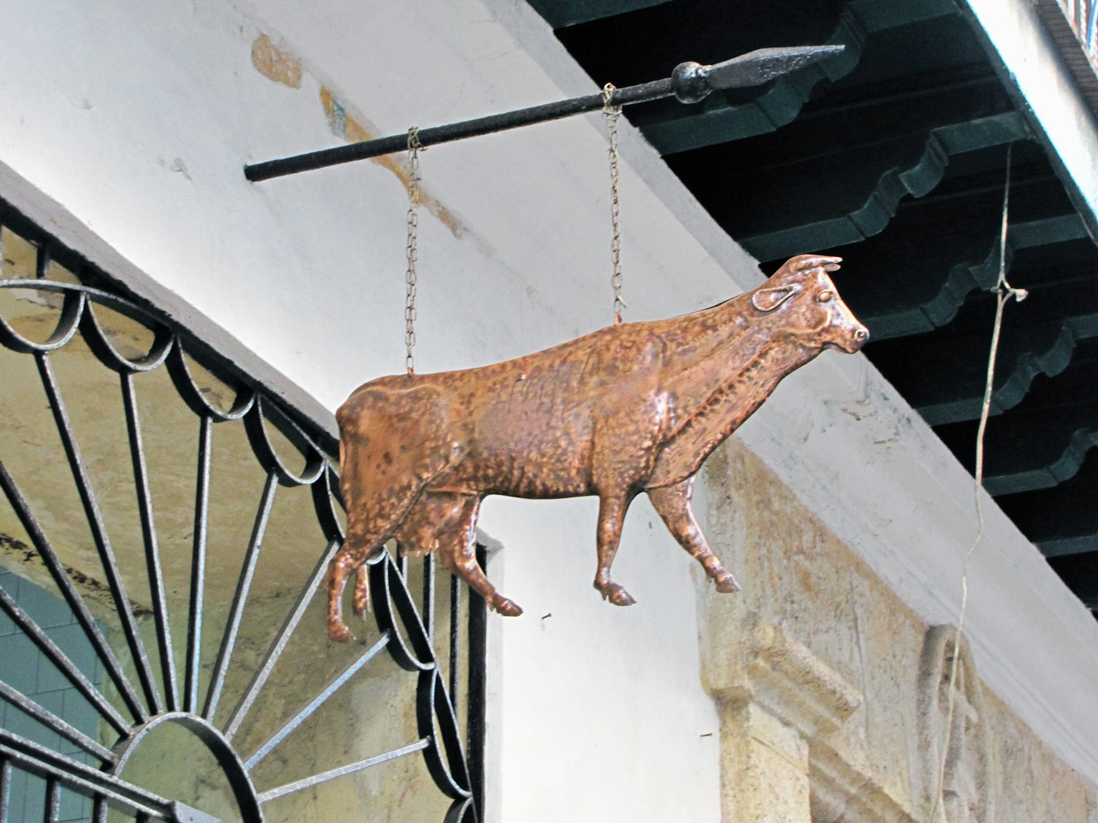 Cartel de bronce en forma de vaca colgado fuera de un edificio