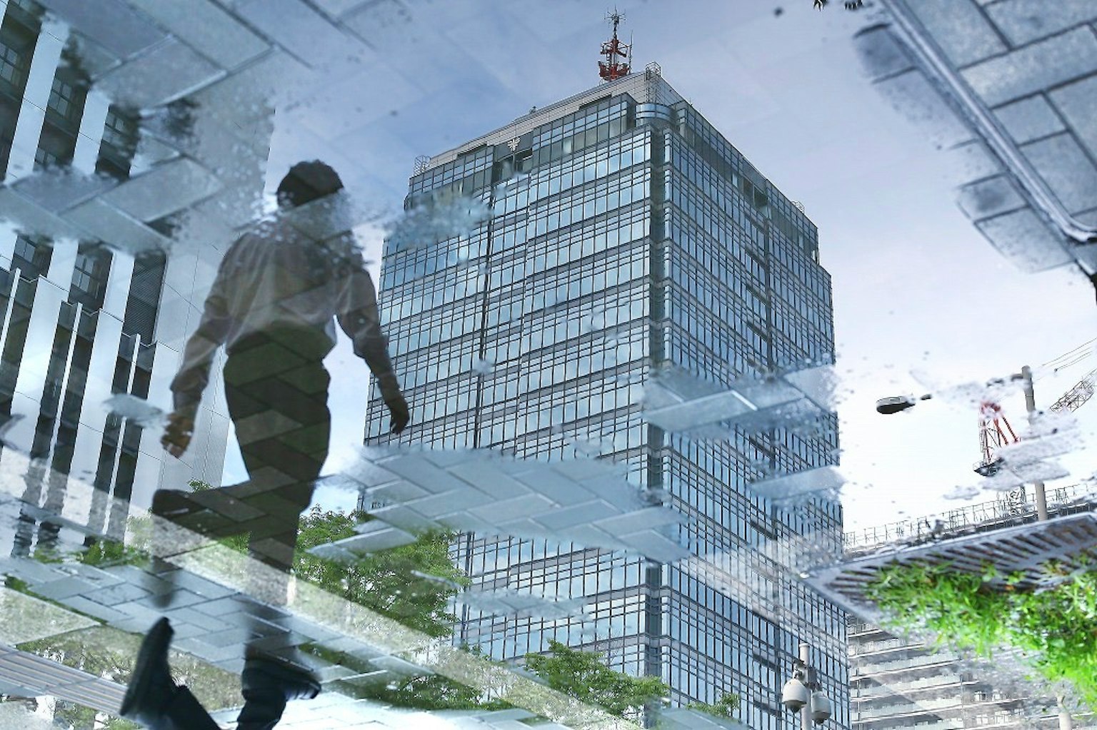 A person walking on glass above a cityscape with reflections
