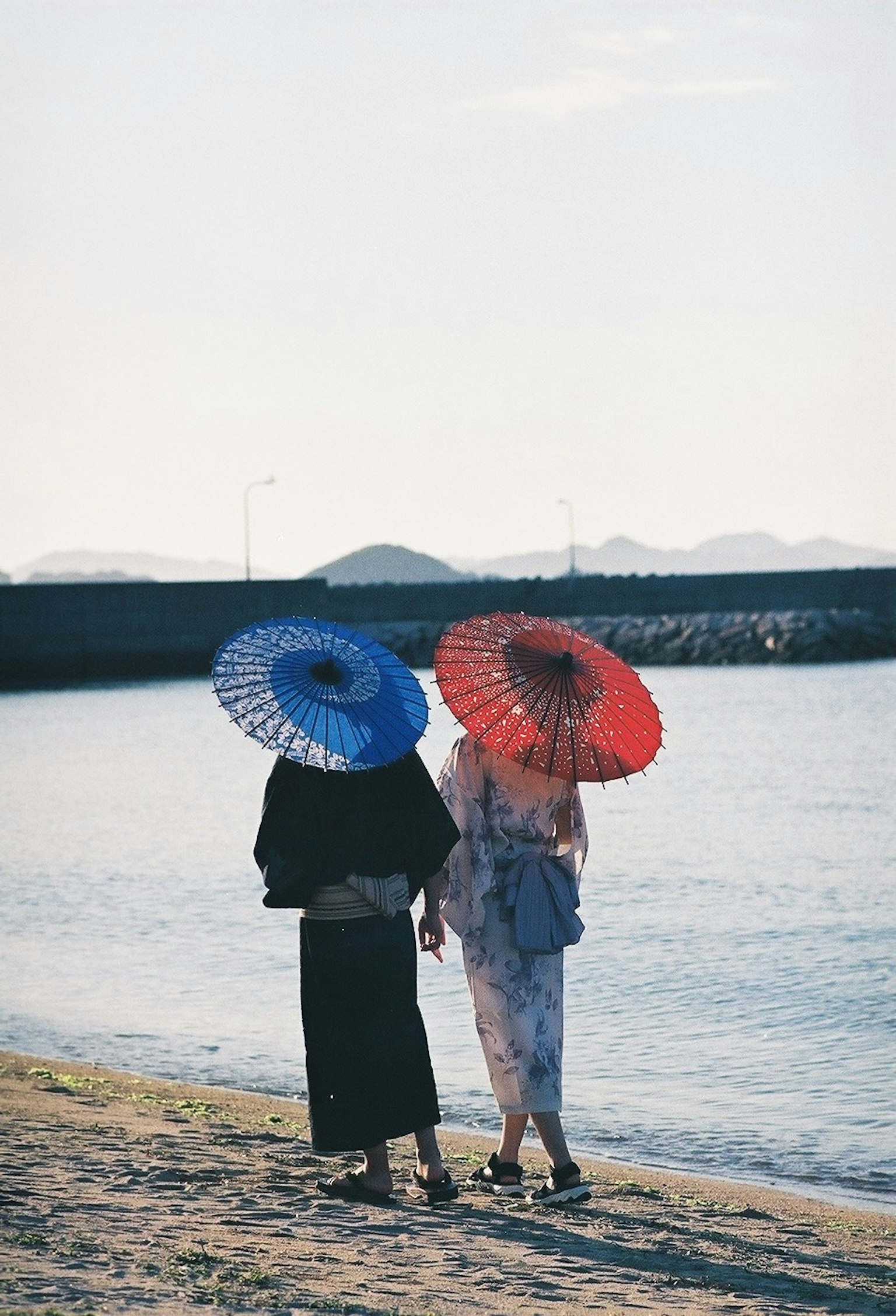 两位女性站在海边，手持传统伞